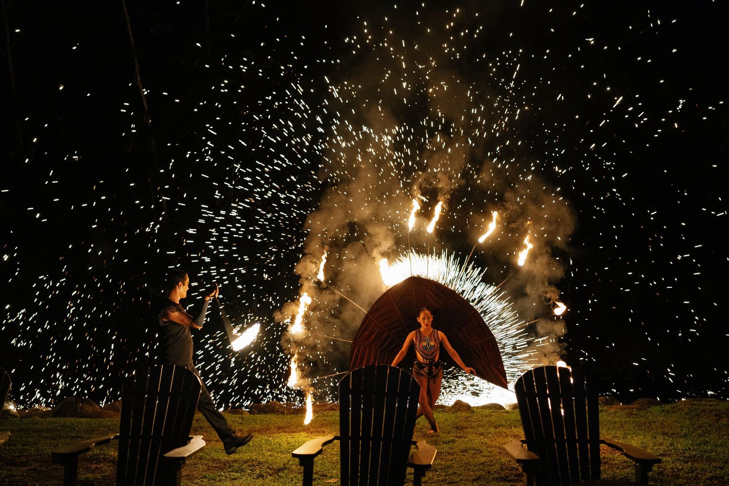 Sparklers create a magical light display against the night sky at an outdoor celebration.