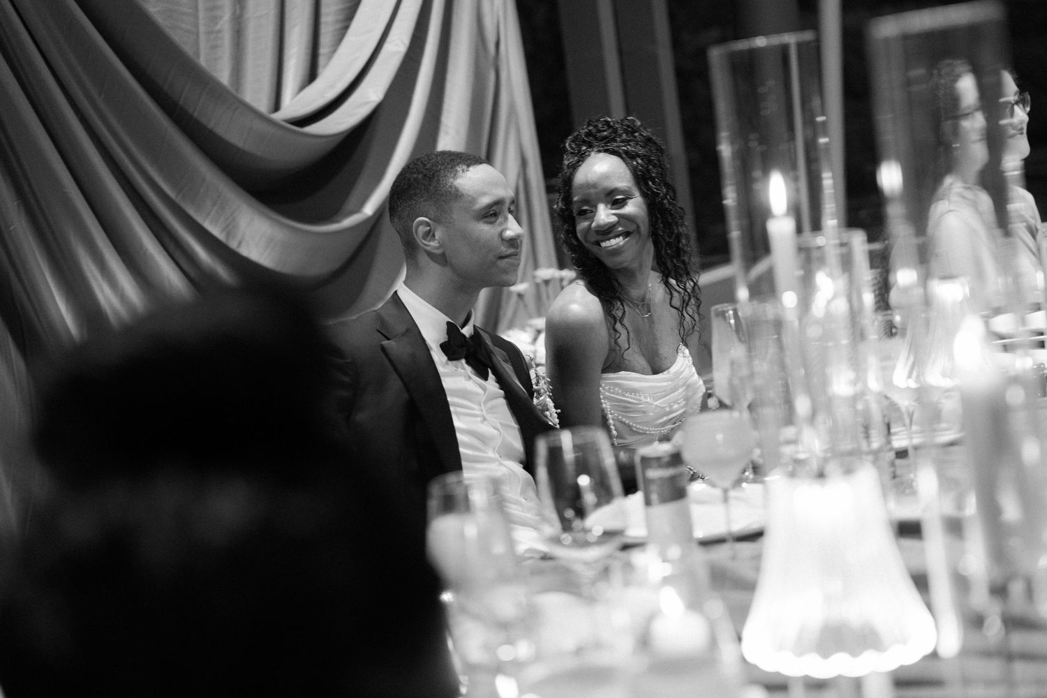 Black and white photo of guests mingling at an elegant reception with glassware.
