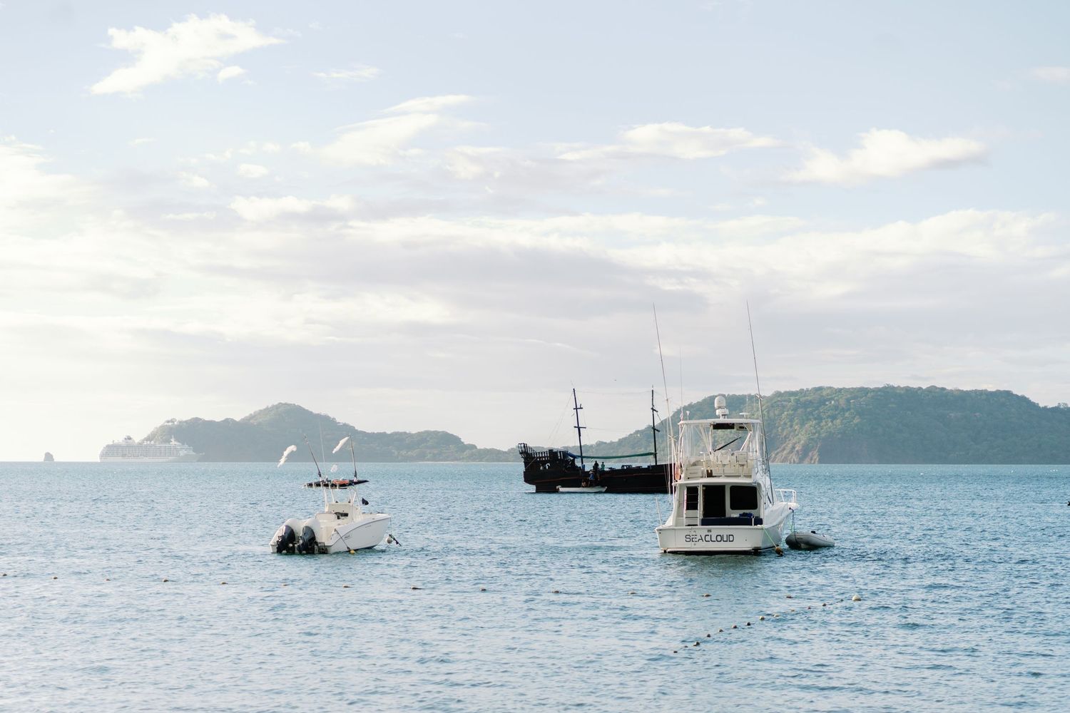 Serene ocean view with boats anchored in bay against mountain backdrop.