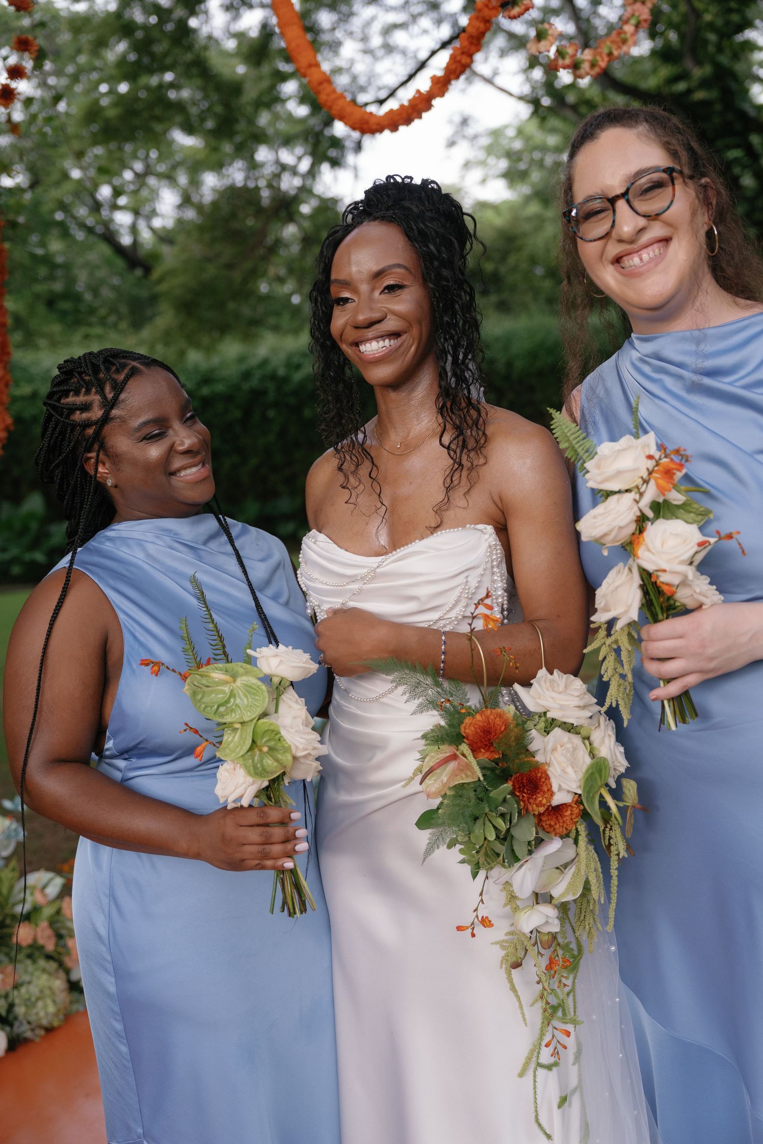 Wedding party members in light blue and white dresses holding floral bouquets.