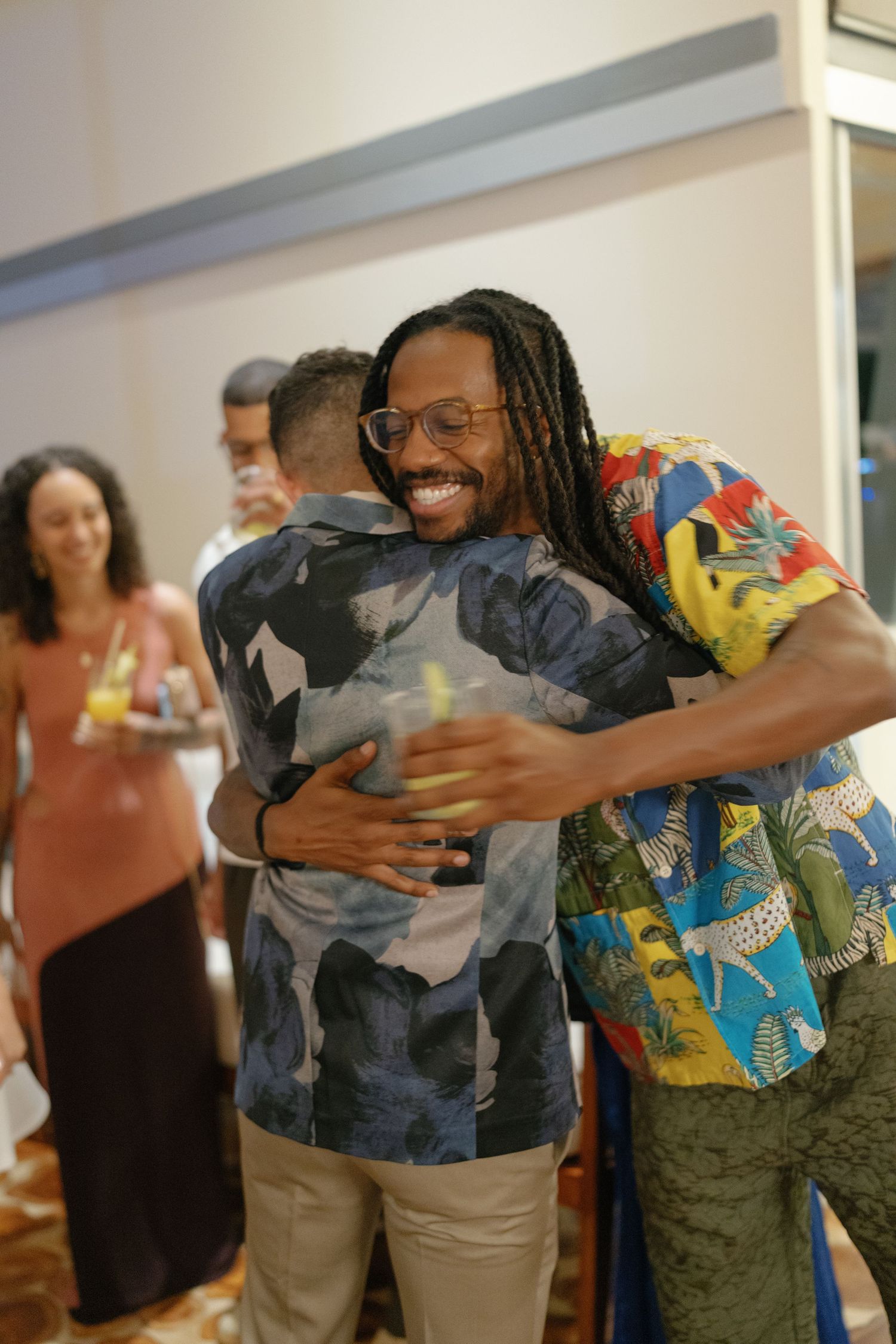 Group of people sharing warm embraces at a casual indoor gathering.