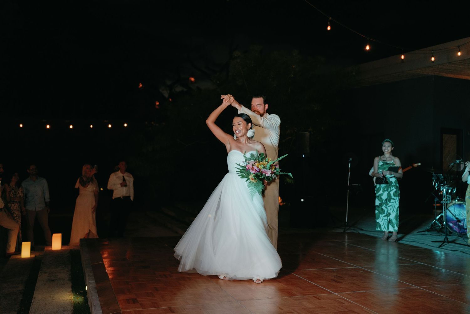 Wedding reception dance floor illuminated by string lights under the night sky.