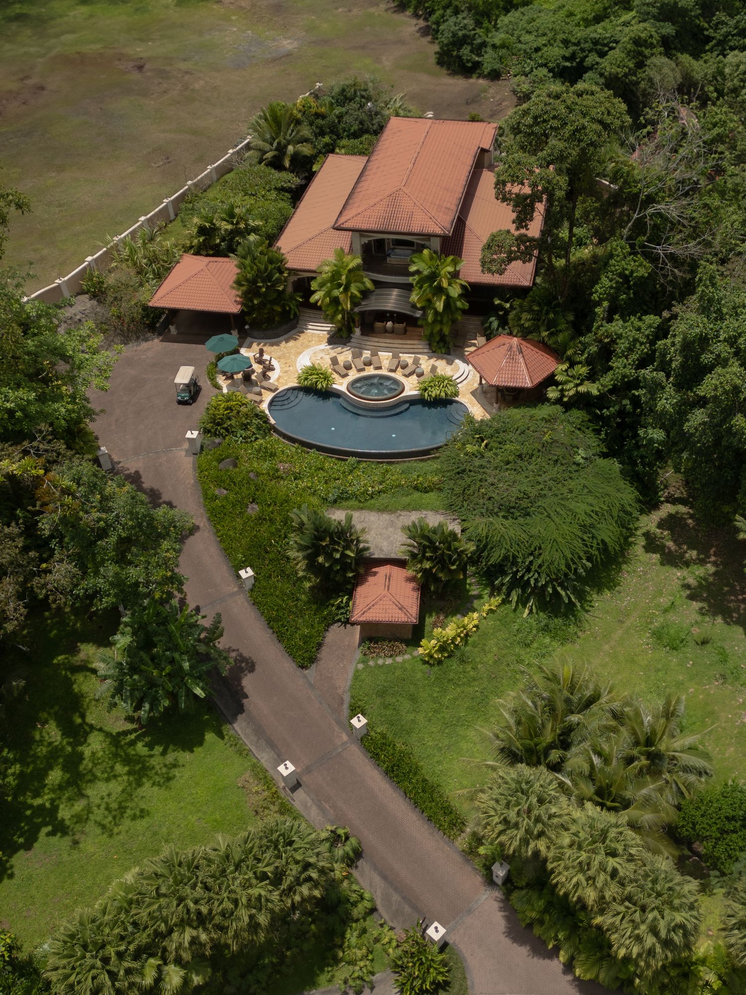 Aerial view of a tropical resort property with swimming pool, buildings, and lush landscaping.