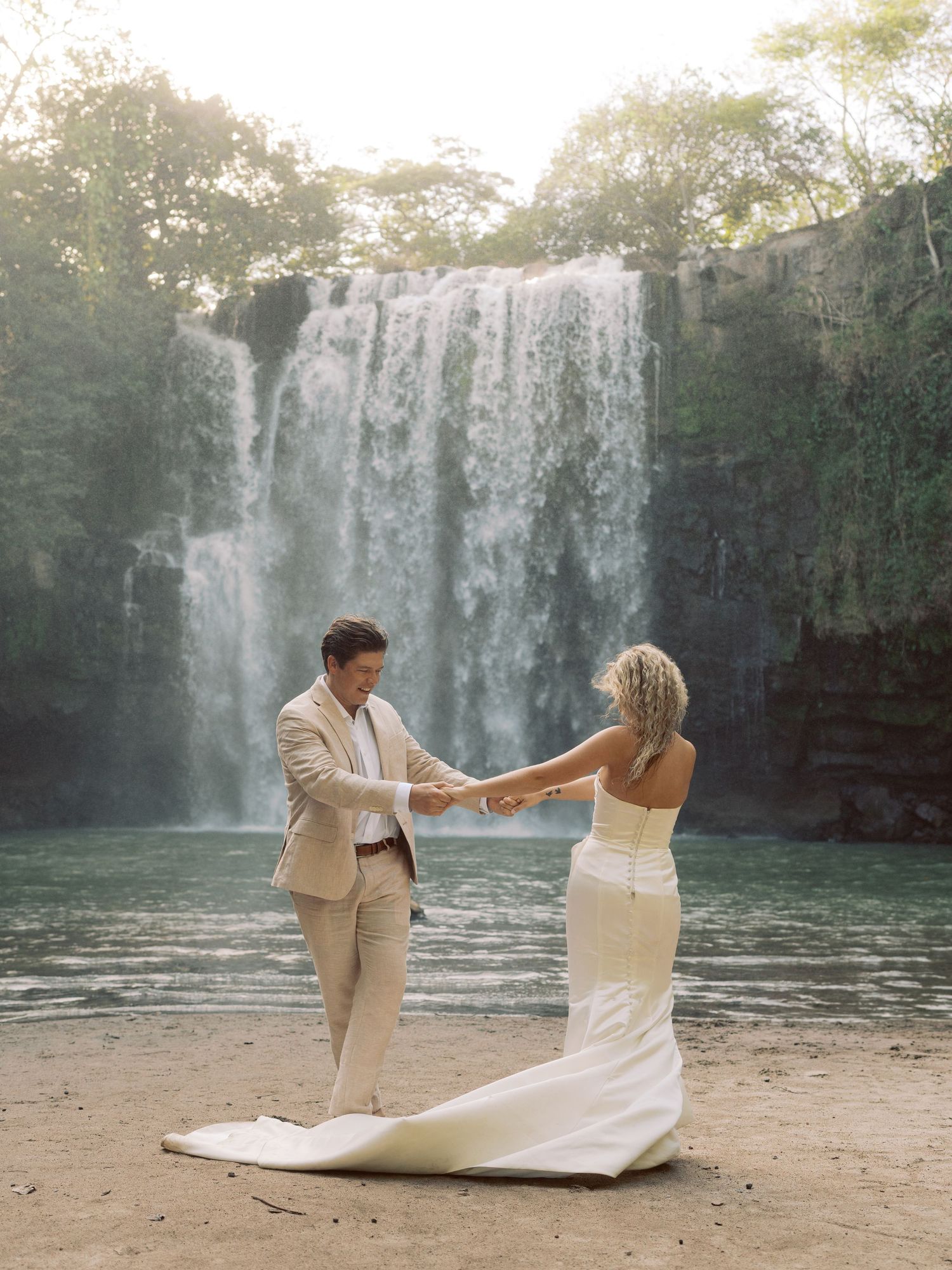 Wedding photo sequence by a majestic waterfall showing romantic poses in formal attire.