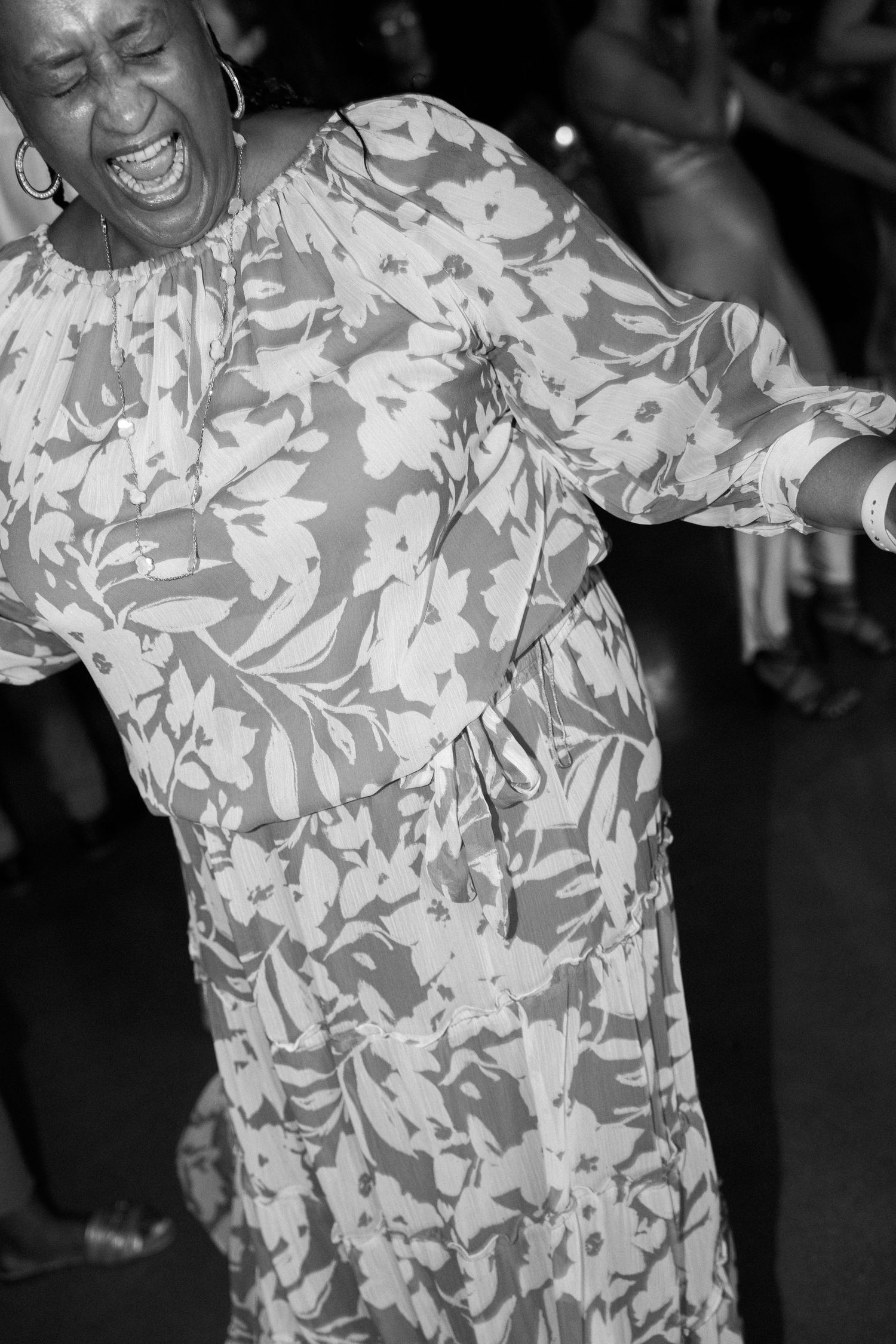 Person in floral print dress dancing joyfully at a celebration.