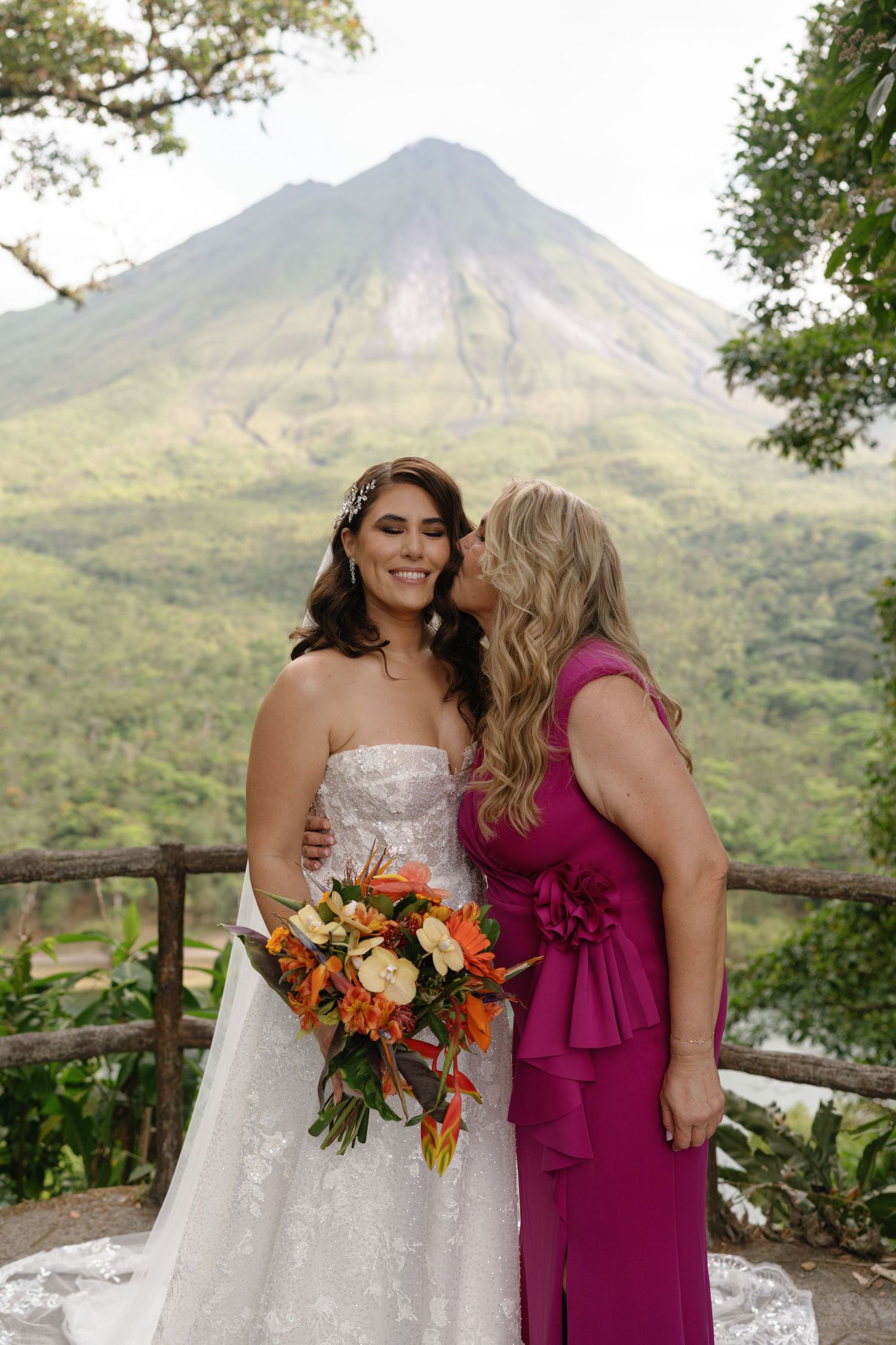 Wedding photos with tropical mountain scenery and bright orange floral bouquet.