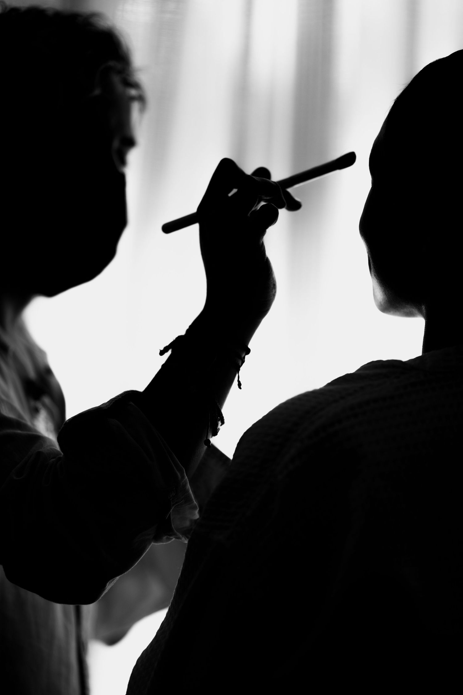 Silhouette of makeup application during wedding preparation.