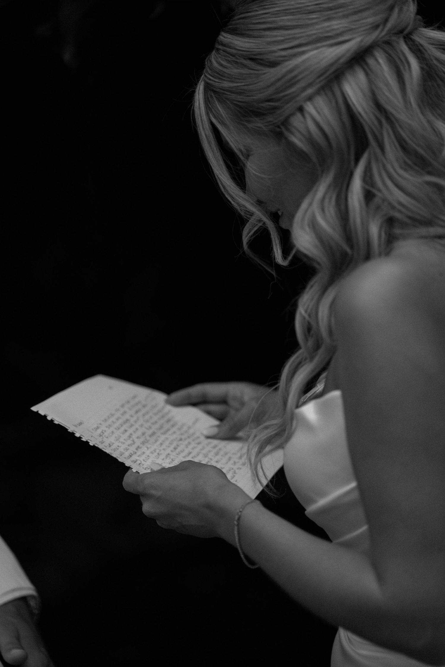 Black and white image of person reading handwritten letter.