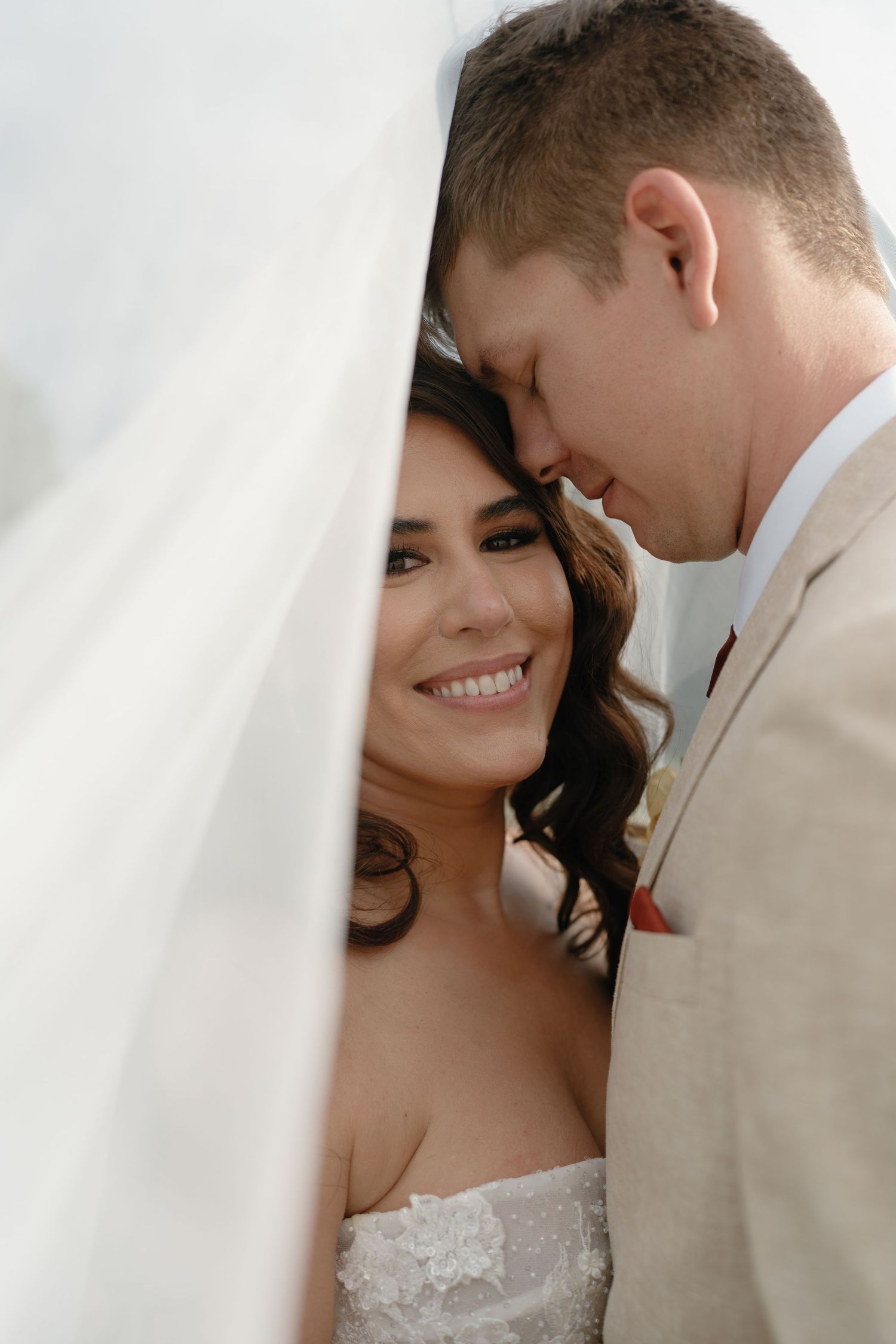 Intimate wedding portrait captured against white background with soft lighting.