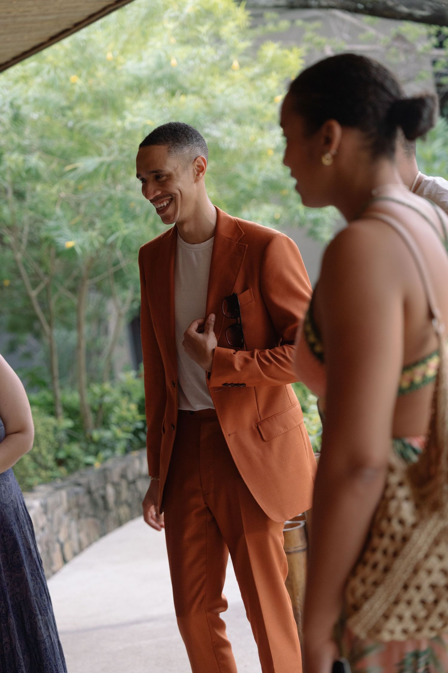 Wedding party members in orange and casual attire gathered on an outdoor pathway.