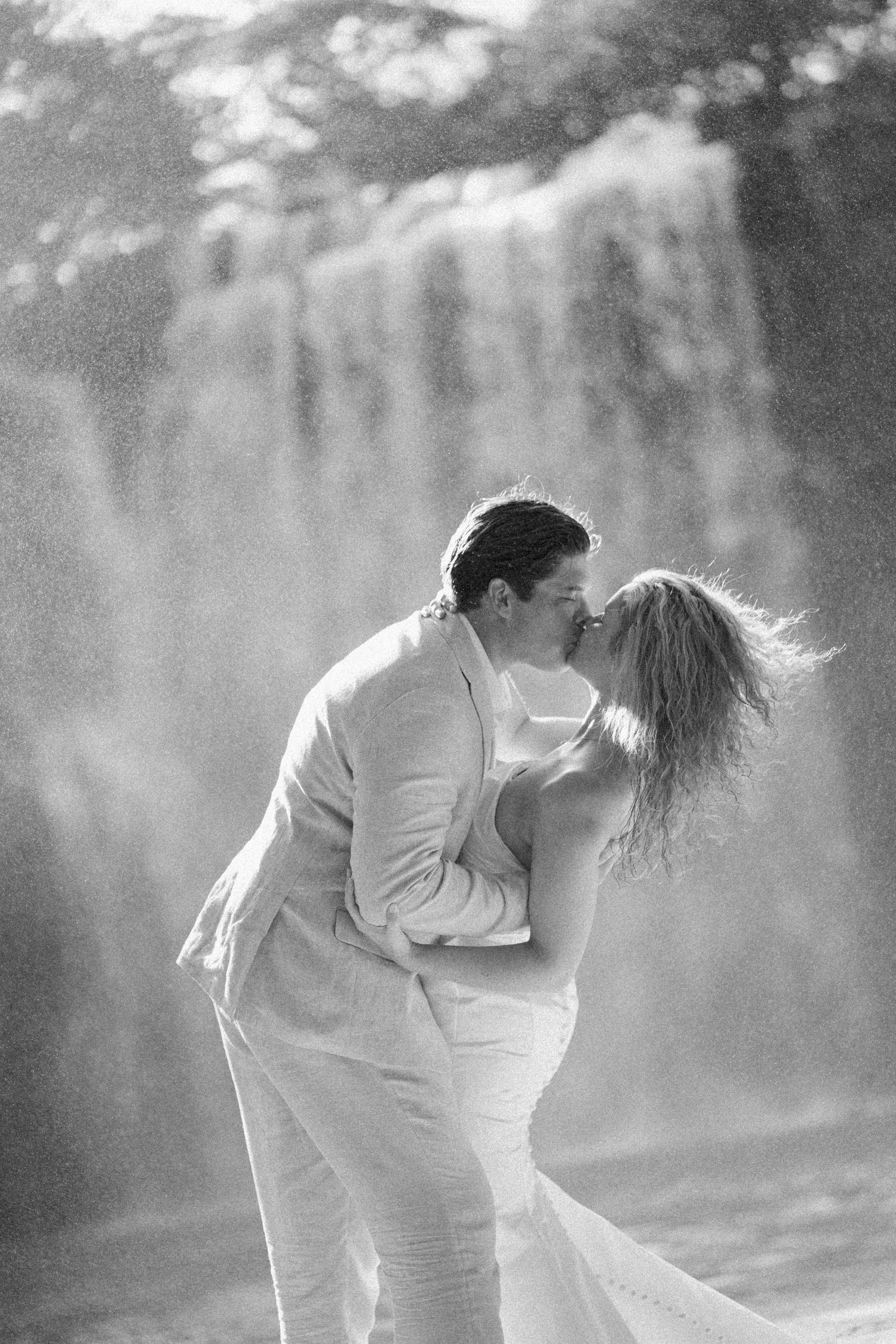 Black and white photo captures intimate dance movements near a cascading waterfall.