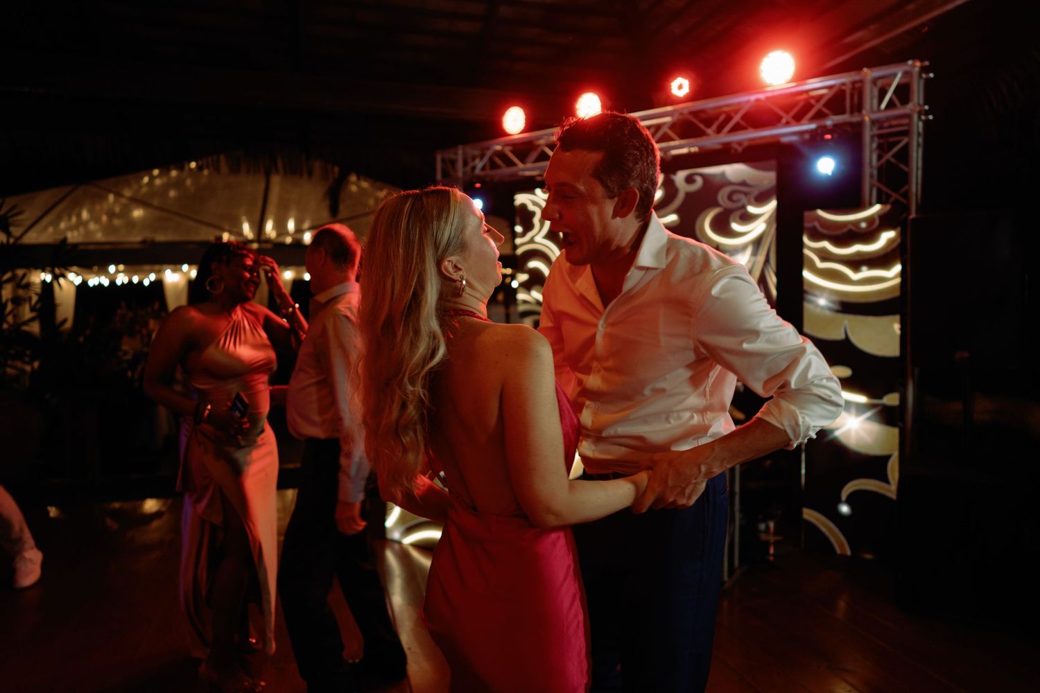 Wedding reception dance floor illuminated with red lighting and party atmosphere.