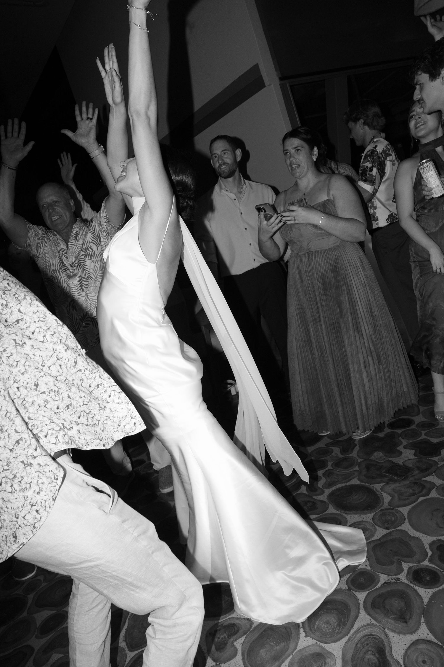 Black and white photos show dancers in formal attire performing energetic dance moves on a patterned floor at a party.