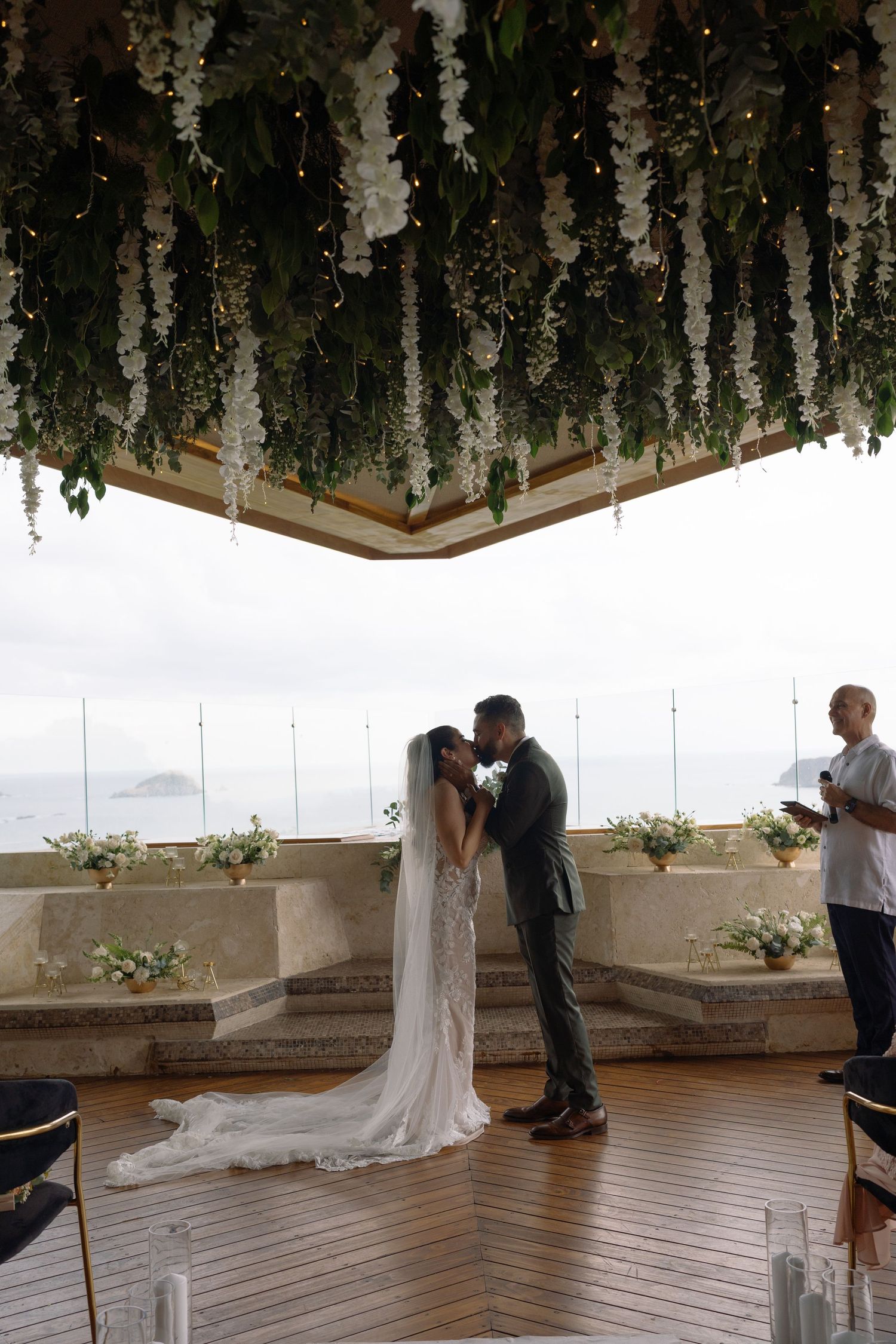Wedding ceremony space with hanging floral installations and wooden deck overlooking the ocean.
