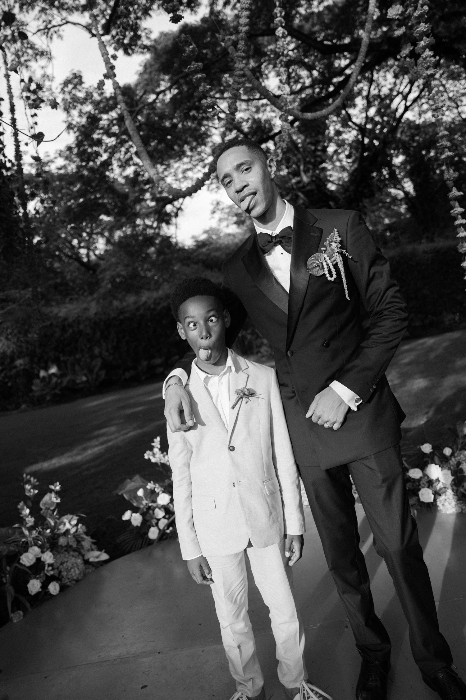 Black and white photo of wedding party members sharing a candid moment outdoors.