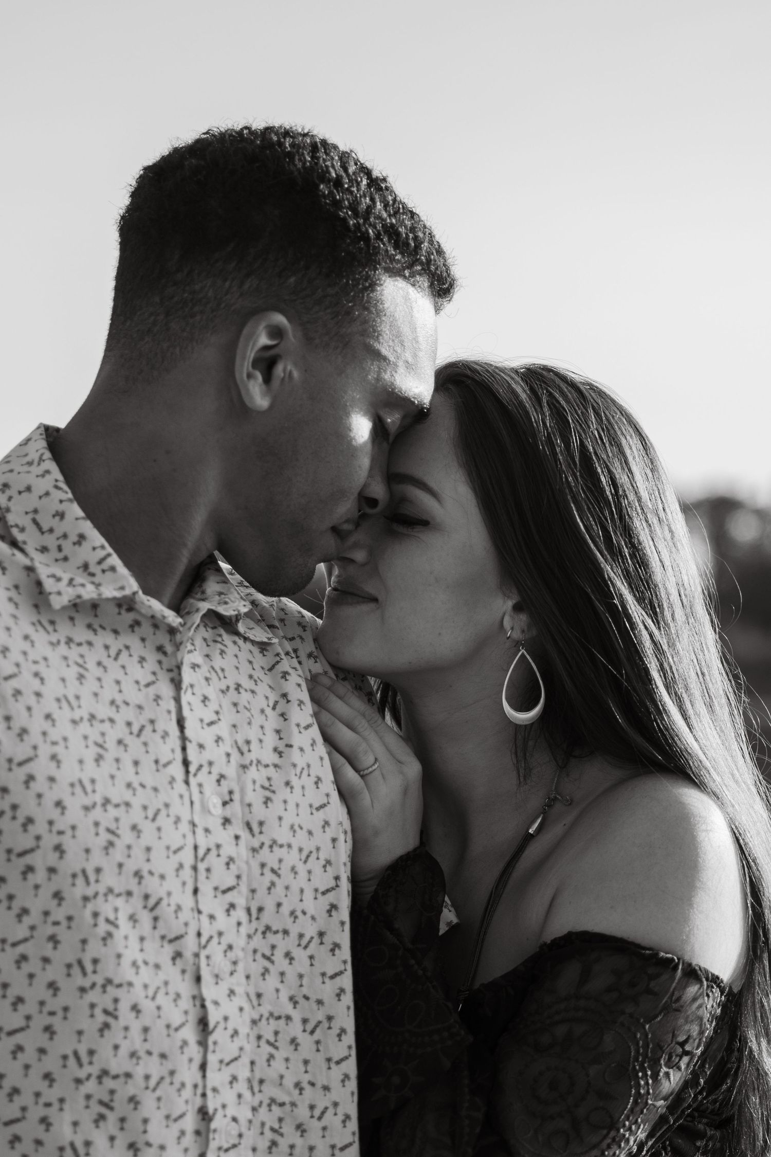 Black and white portrait of couple sharing intimate moment outdoors.
