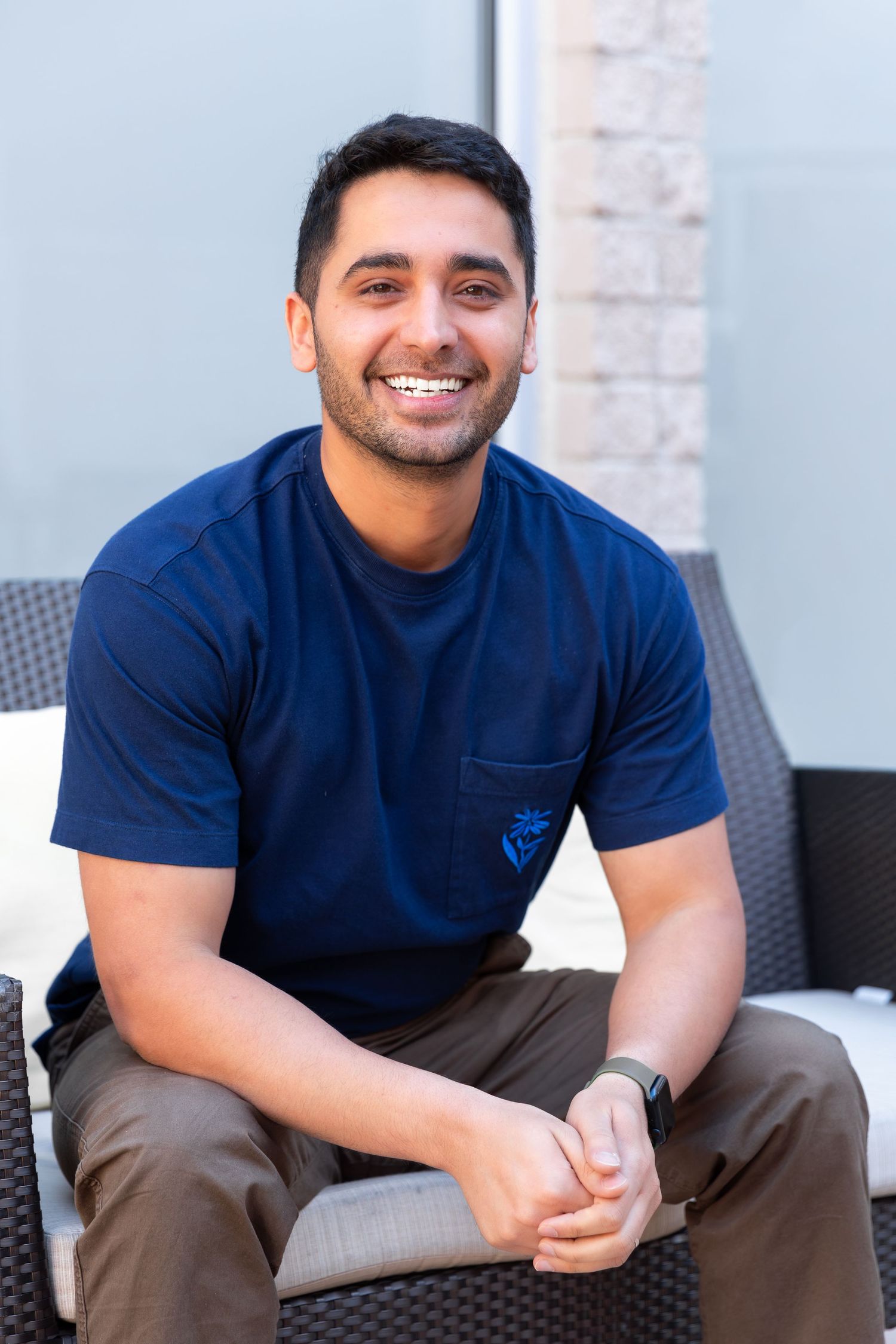 Person in navy t-shirt sitting outdoors with a friendly expression.