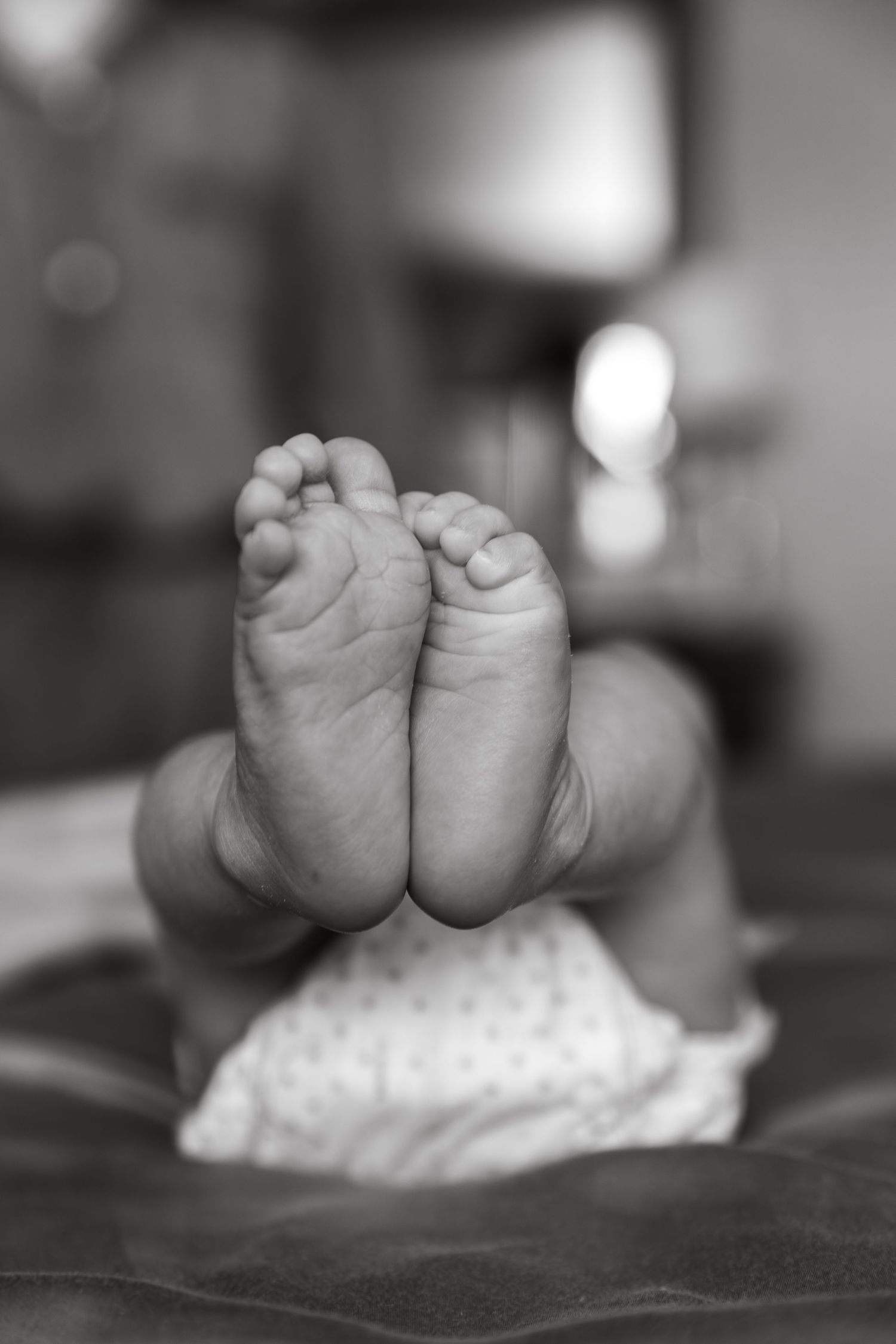 Close-up black and white photo series of tiny baby feet against a textured background.