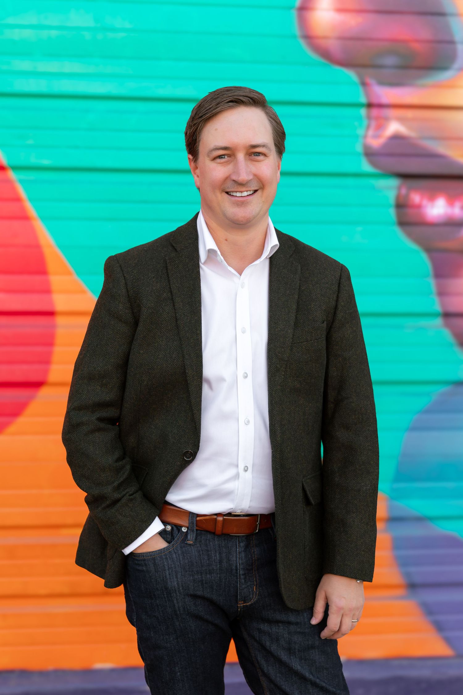 Professional headshots against a vibrant turquoise and orange wall showing confident business attire.