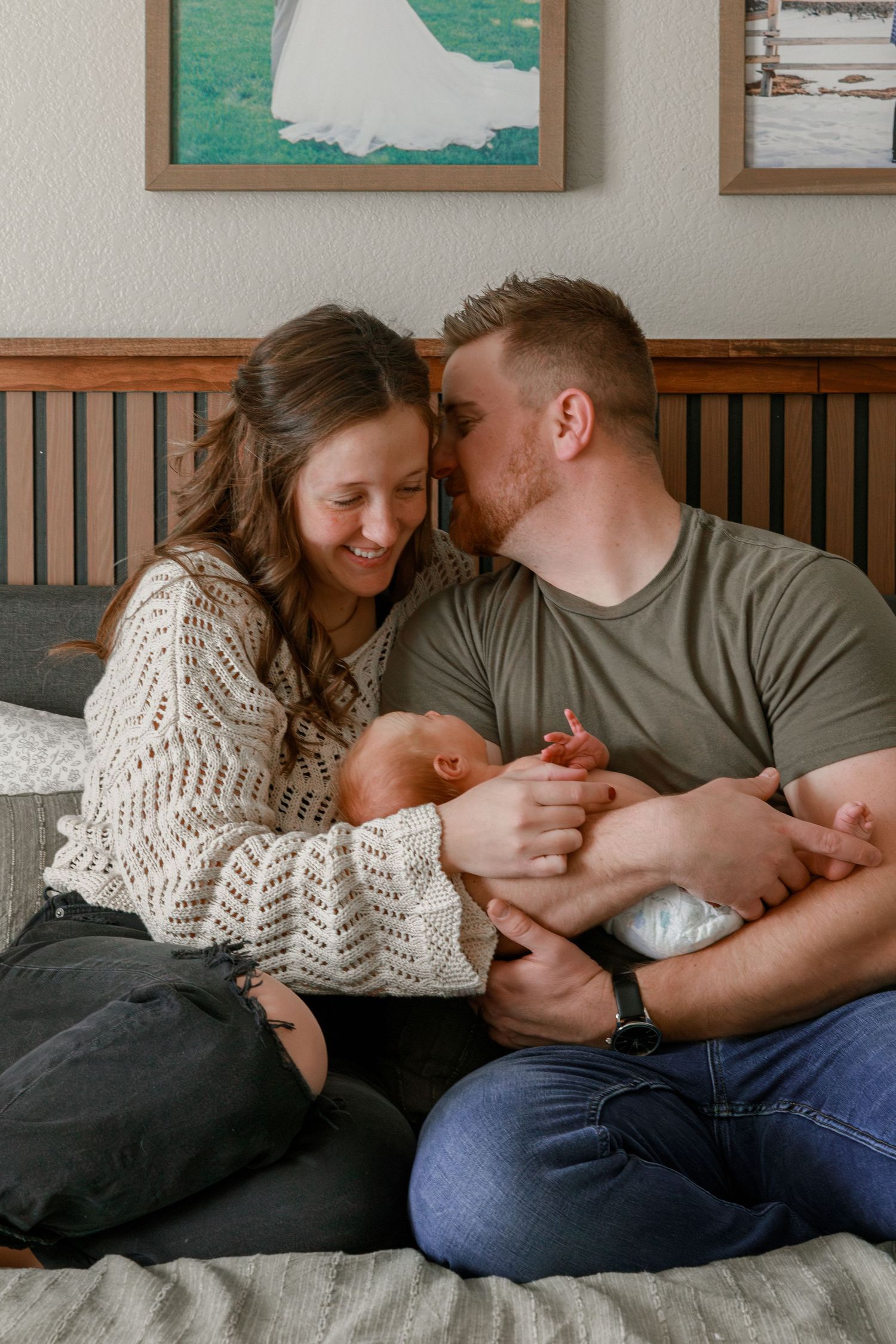 Intimate family moment captured on a bed with artwork displayed on walls.