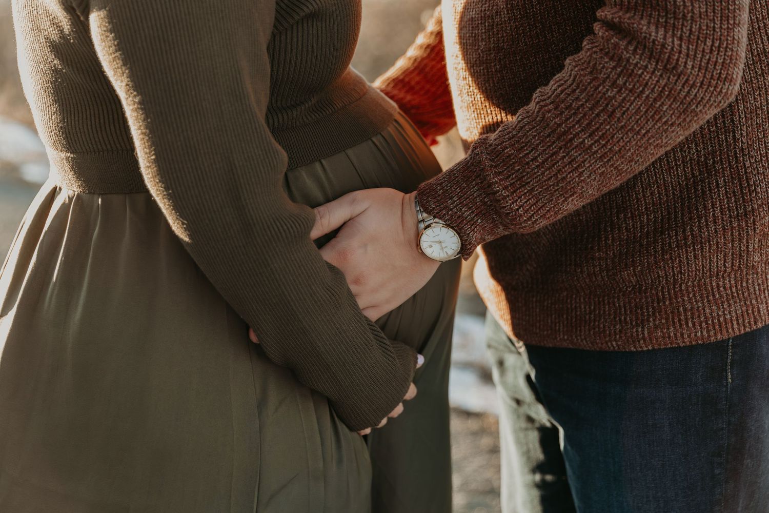 Close-up shots of couple holding sonogram photos while sharing intimate moments in natural lighting.