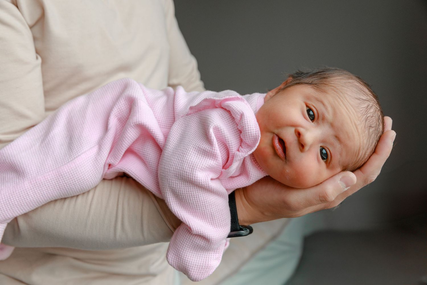 Baby wearing pink outfit lying on white surface.