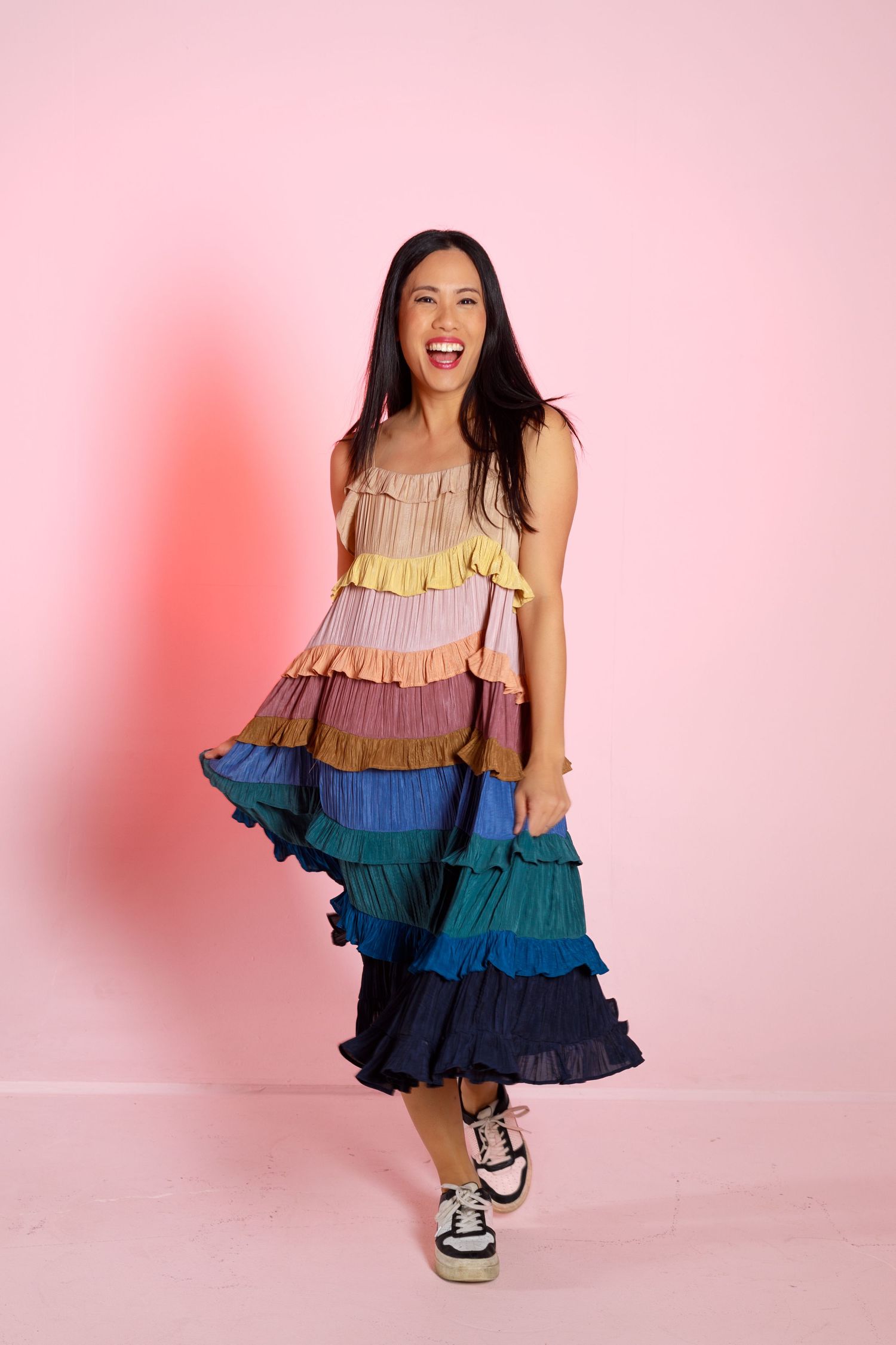 Tiered rainbow ombre dress with ruffles photographed against pink backdrop.