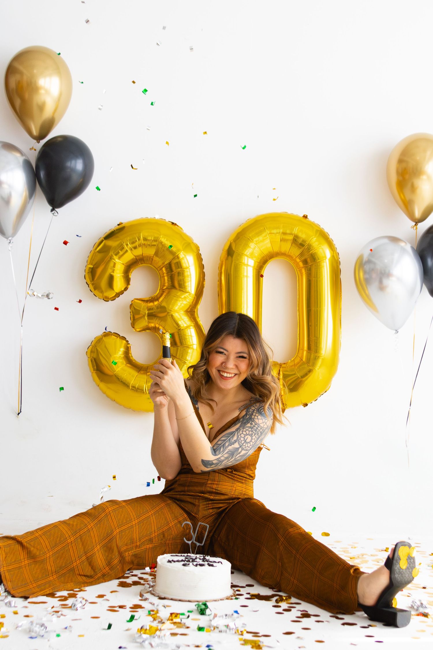 Festive birthday setup with gold balloon numbers and confetti on white background.