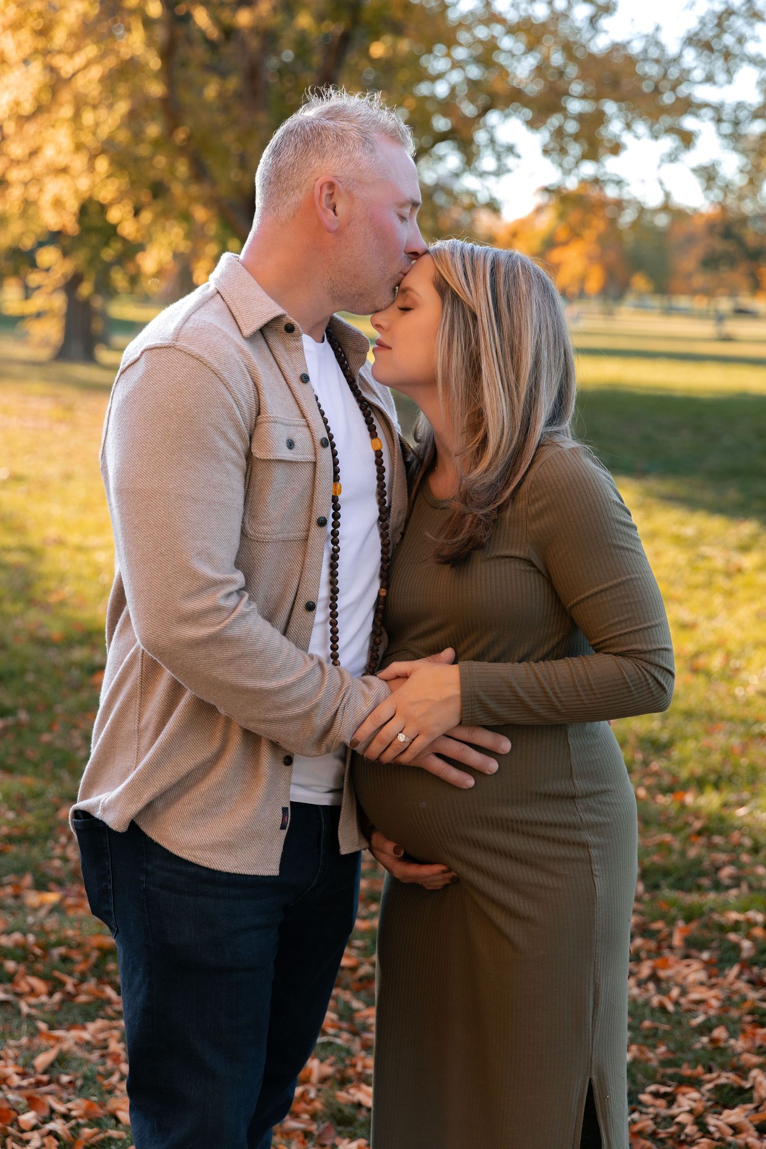 Intimate autumn outdoor portrait of couple embracing among fallen leaves.