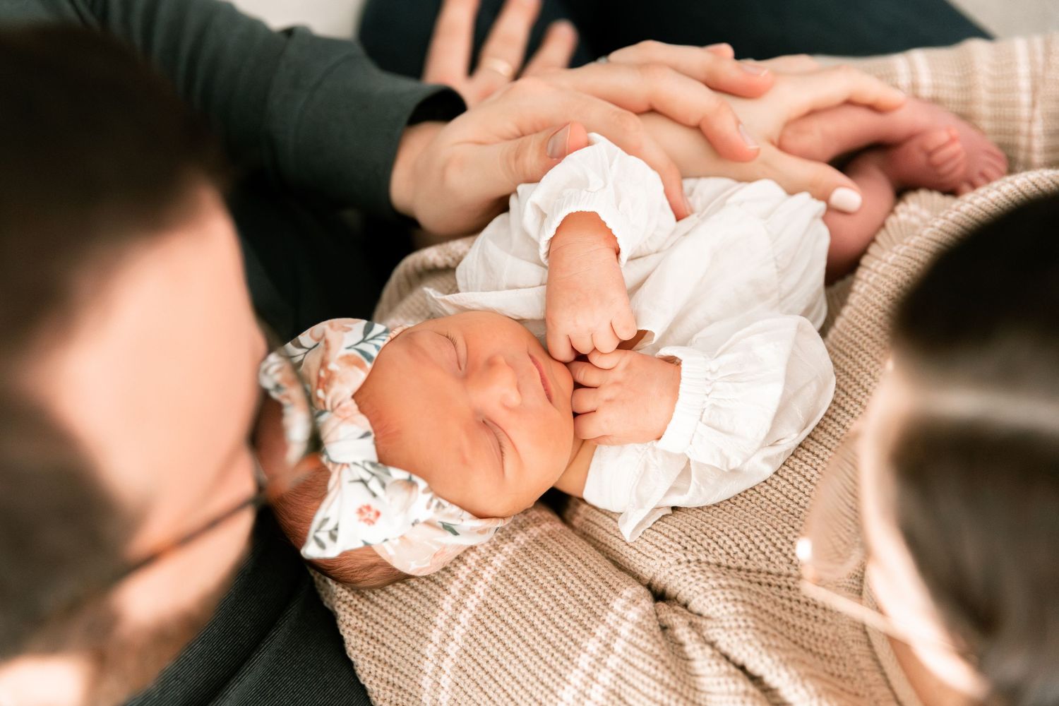 Close-up photo of newborn baby feet wrapped in soft beige knit blanket.