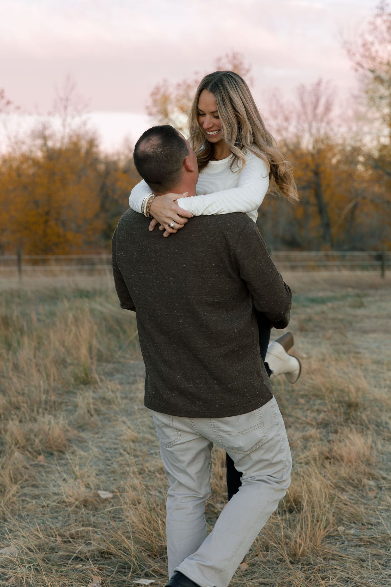 Two people share an intimate dance together in a golden field at dusk.