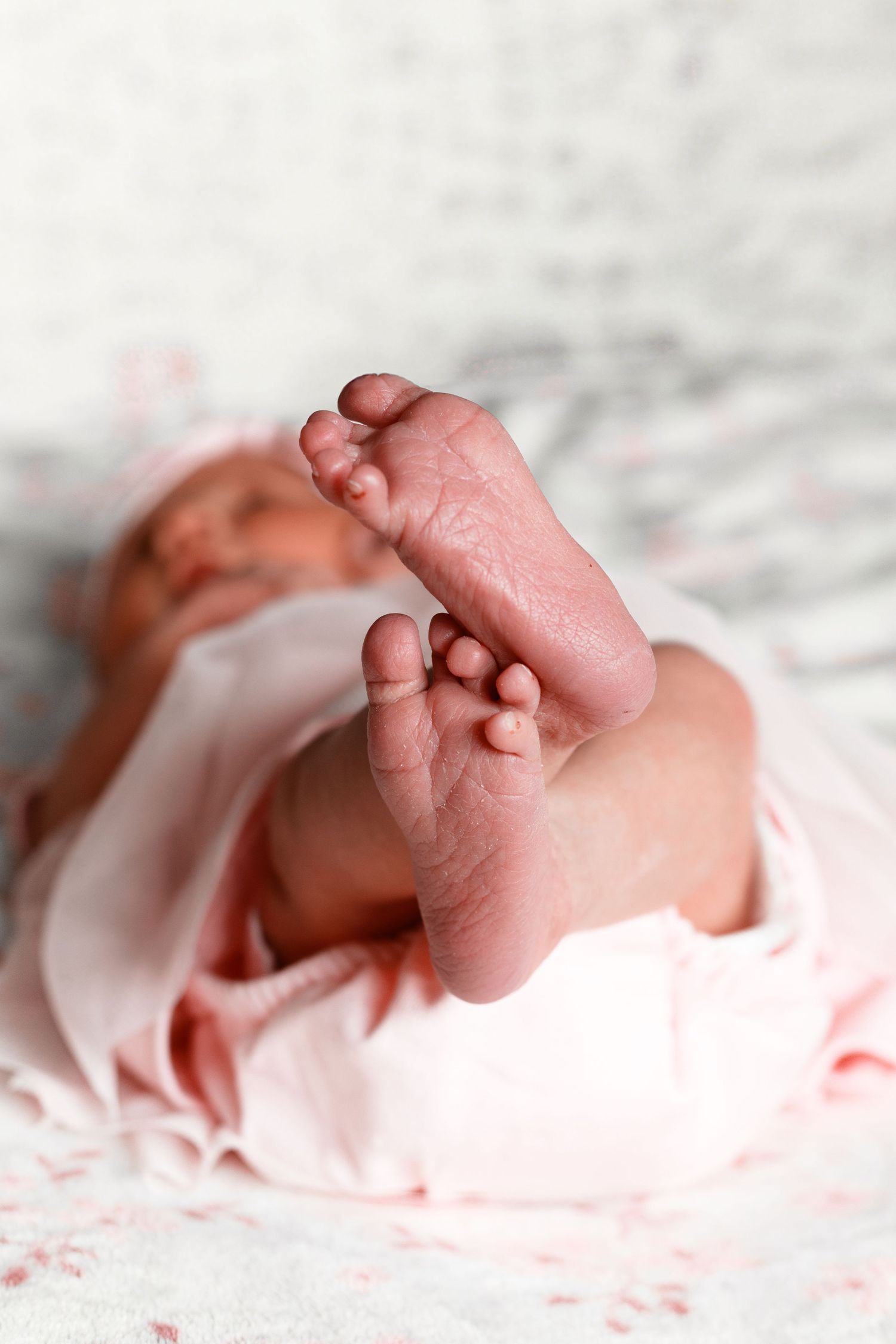 Close-up of tiny newborn baby feet on soft white fabric.