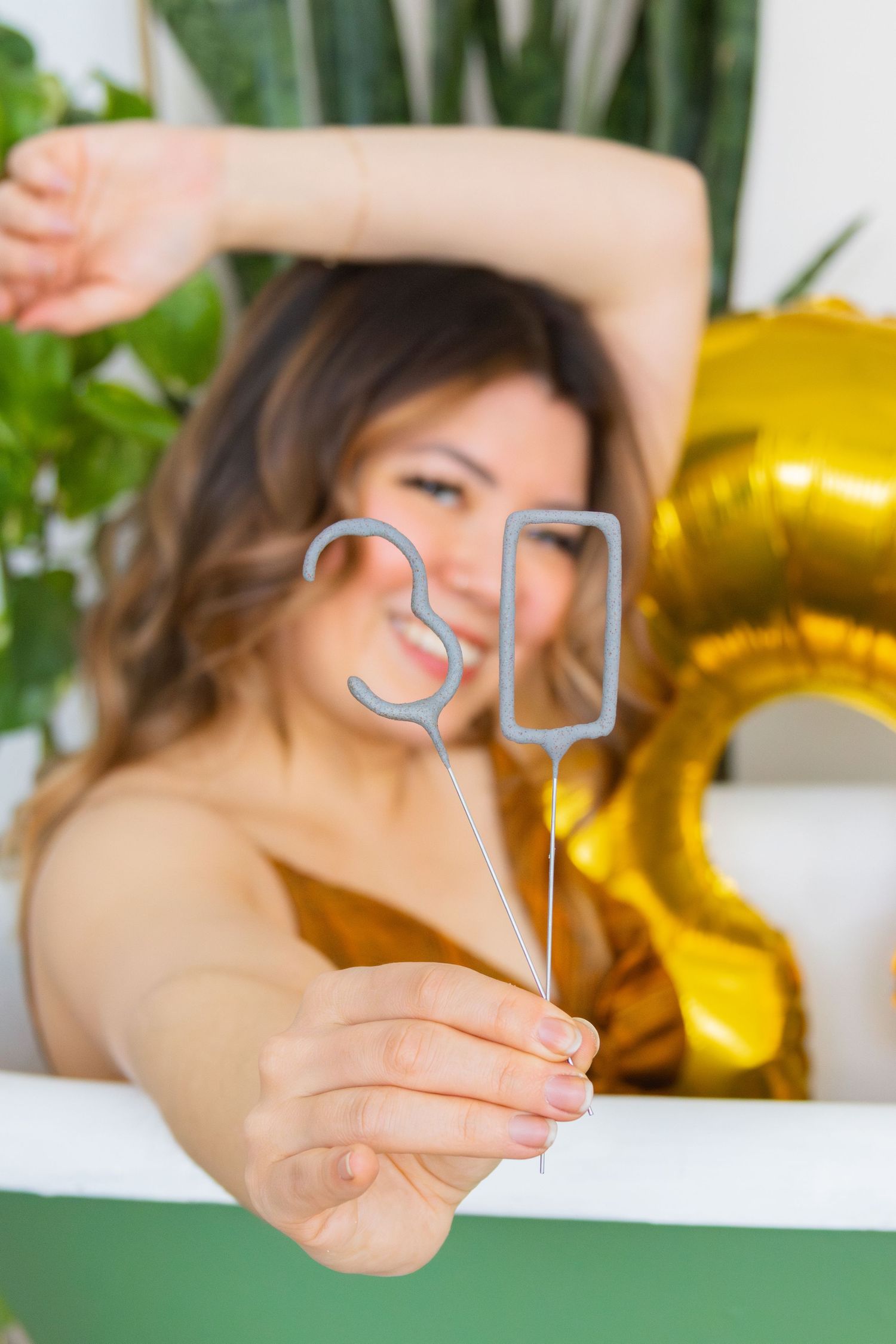 Someone holding silver number 30 decorations with a gold balloon in the background.