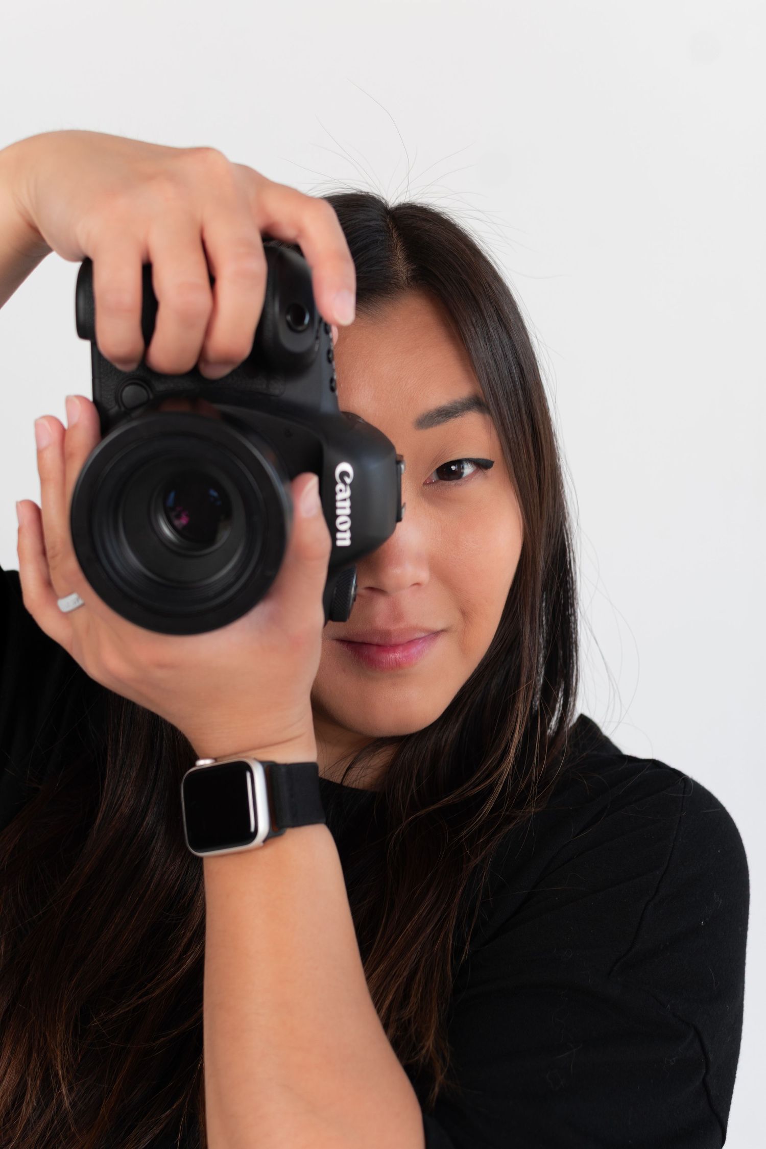 Photographer holding black DSLR camera in creative self-portrait series.
