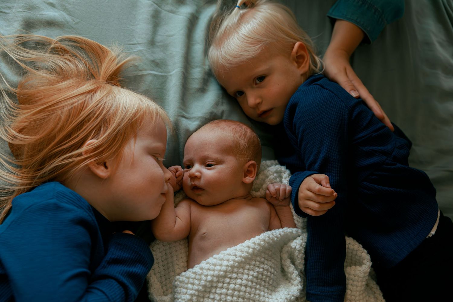 Children sharing tender moments while lying down together.