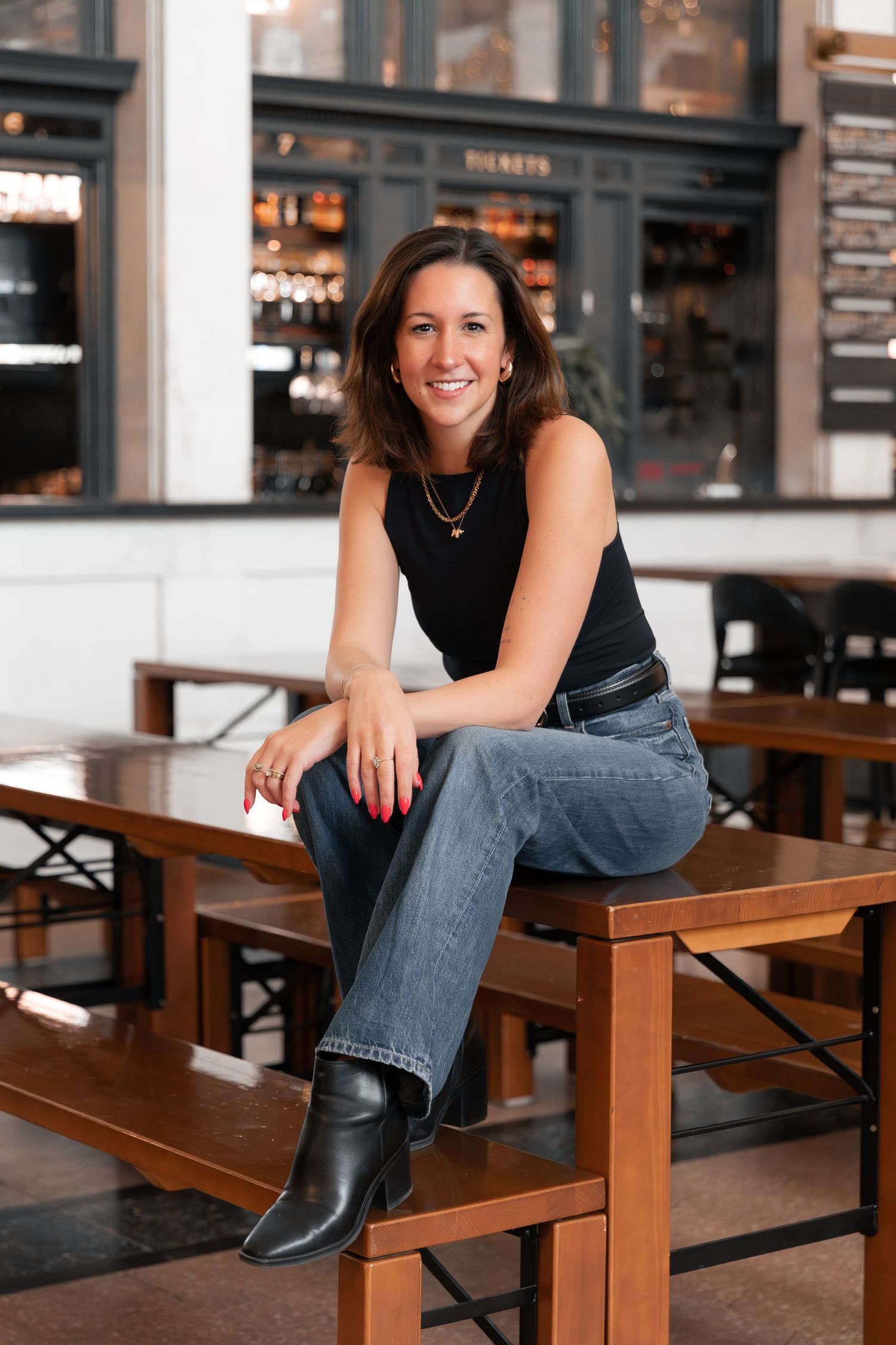A casual portrait series showing someone in jeans and black boots sitting on wooden benches in a modern restaurant setting.