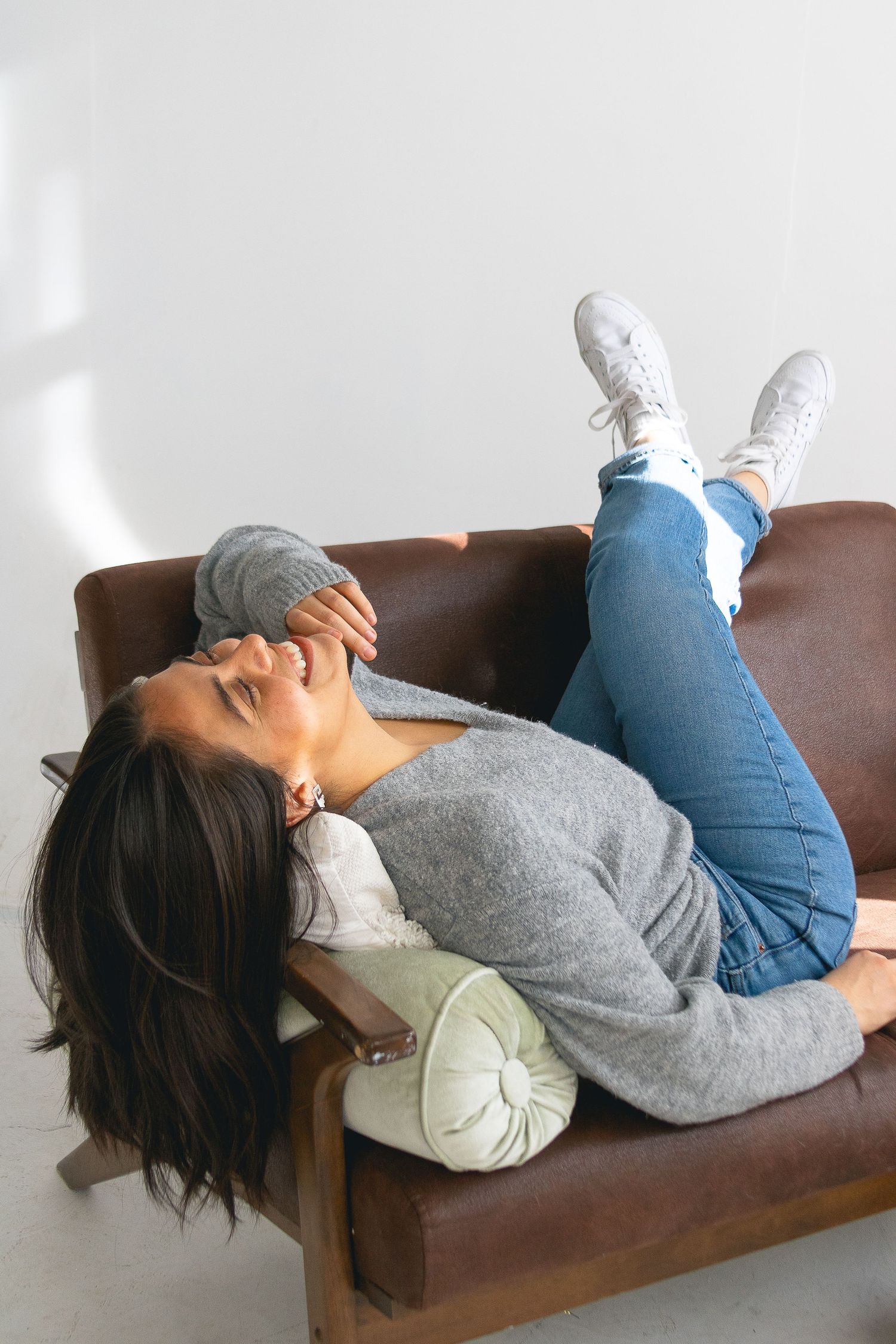 Lifestyle photo of person relaxing on brown leather couch in casual attire.