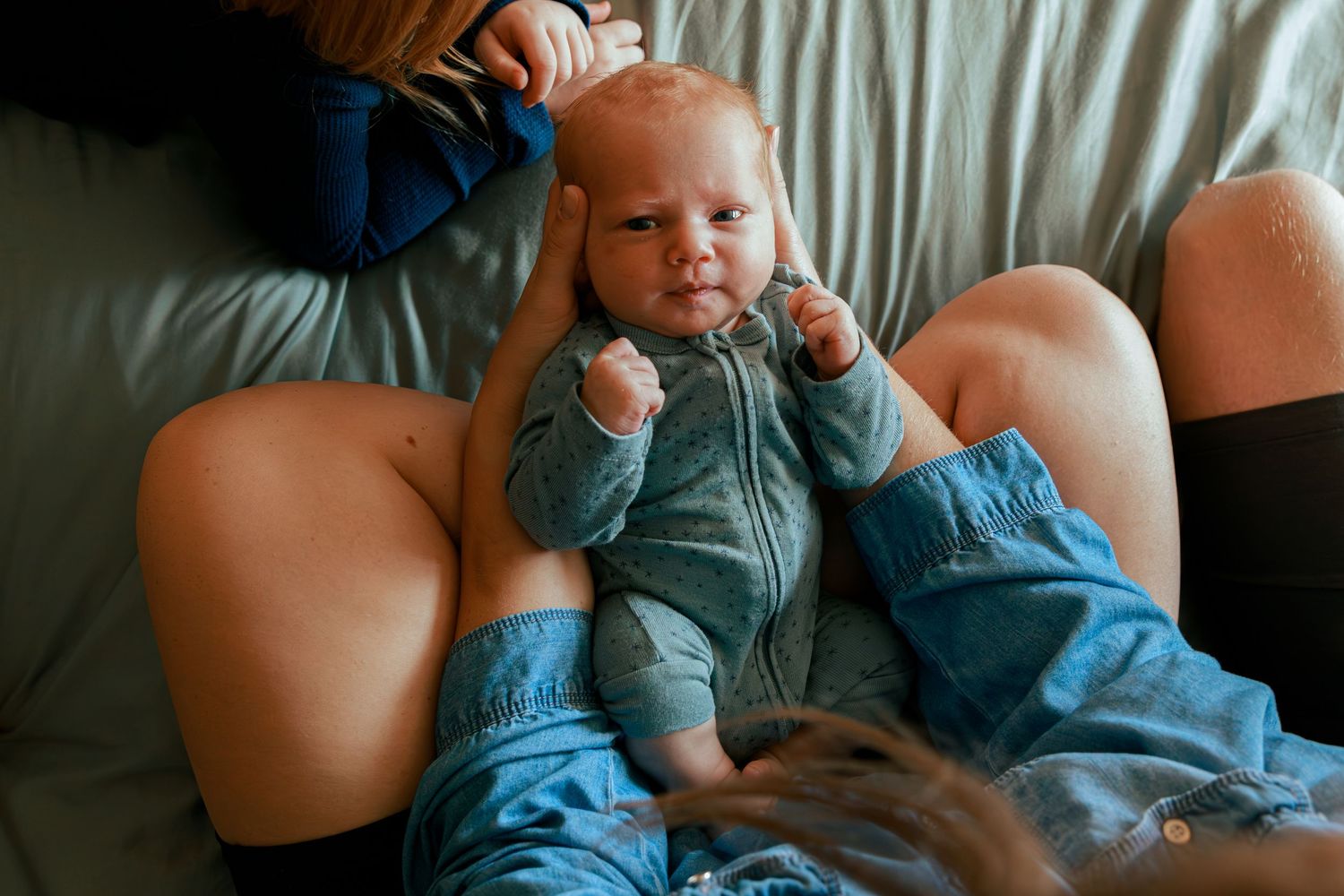 Baby in blue outfit plays and smiles during candid moment.