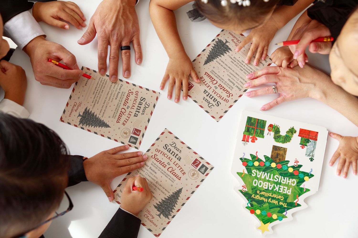 Aerial view of people gathered around a table playing a Packaged Christmas card game with festive holiday cards.