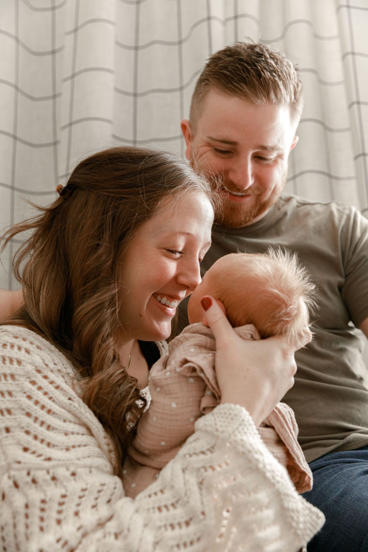 Family shares intimate moment with newborn baby in cozy home setting.
