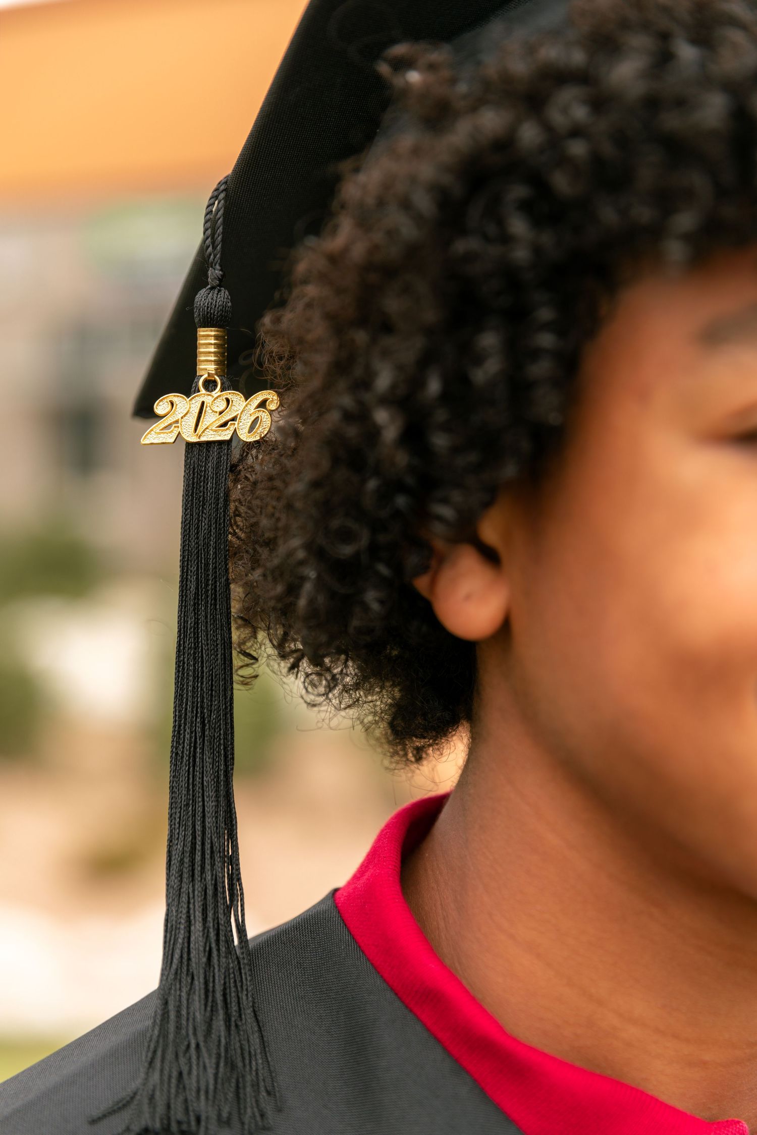 Close-up of a 2026 graduation cap tassel on a student wearing black gown and red shirt.