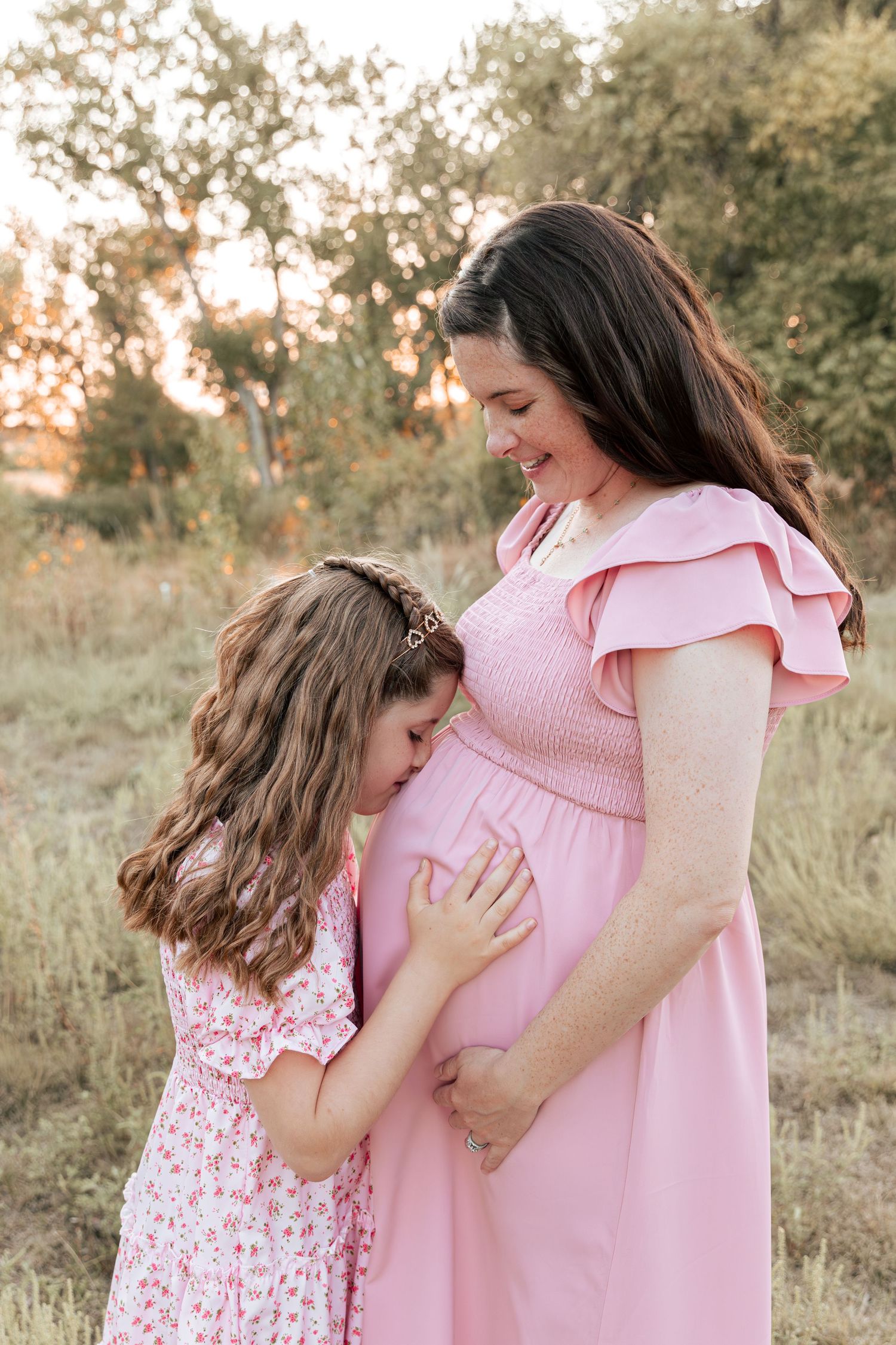 An intimate maternity moment between parent and child outdoors.