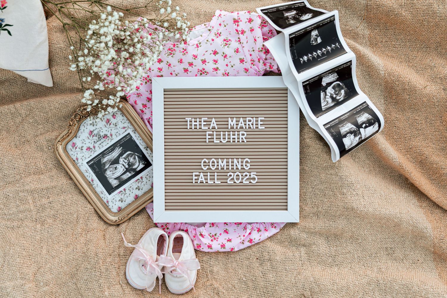 A collection of baby-themed items and ultrasound photos arranged with a letterboard announcement.