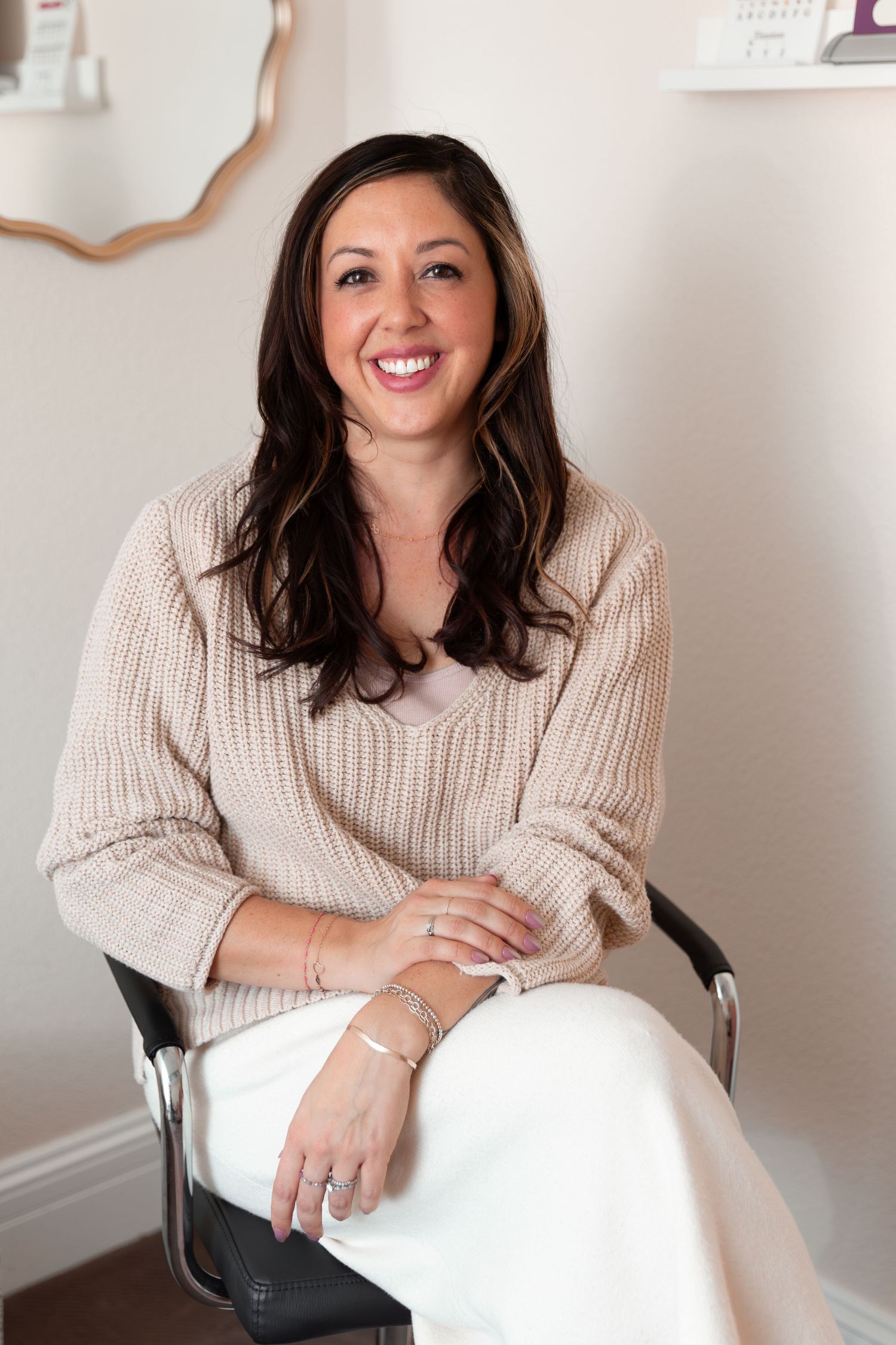 A series of four professional headshots showing someone wearing a beige sweater sitting in a chair against a white wall.