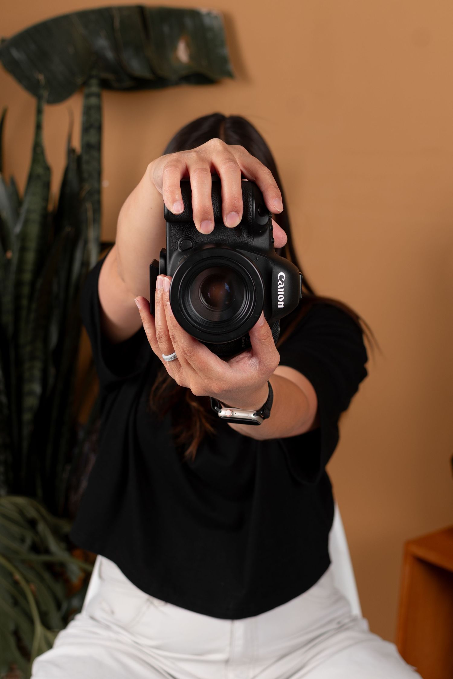 Close-up shots of photographer holding professional camera against warm brown background.