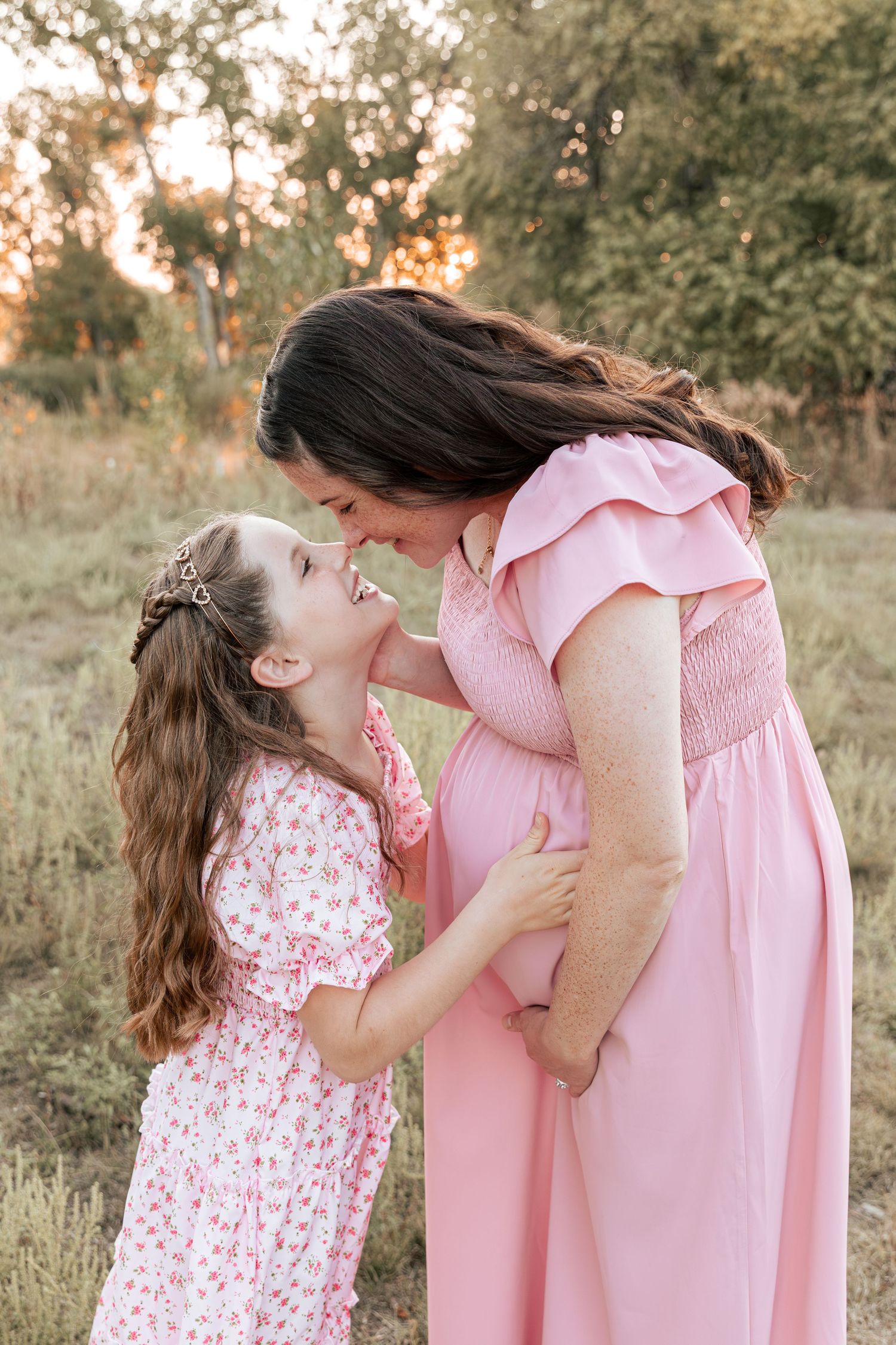 A tender outdoor moment between parent and child wearing matching pink dresses.