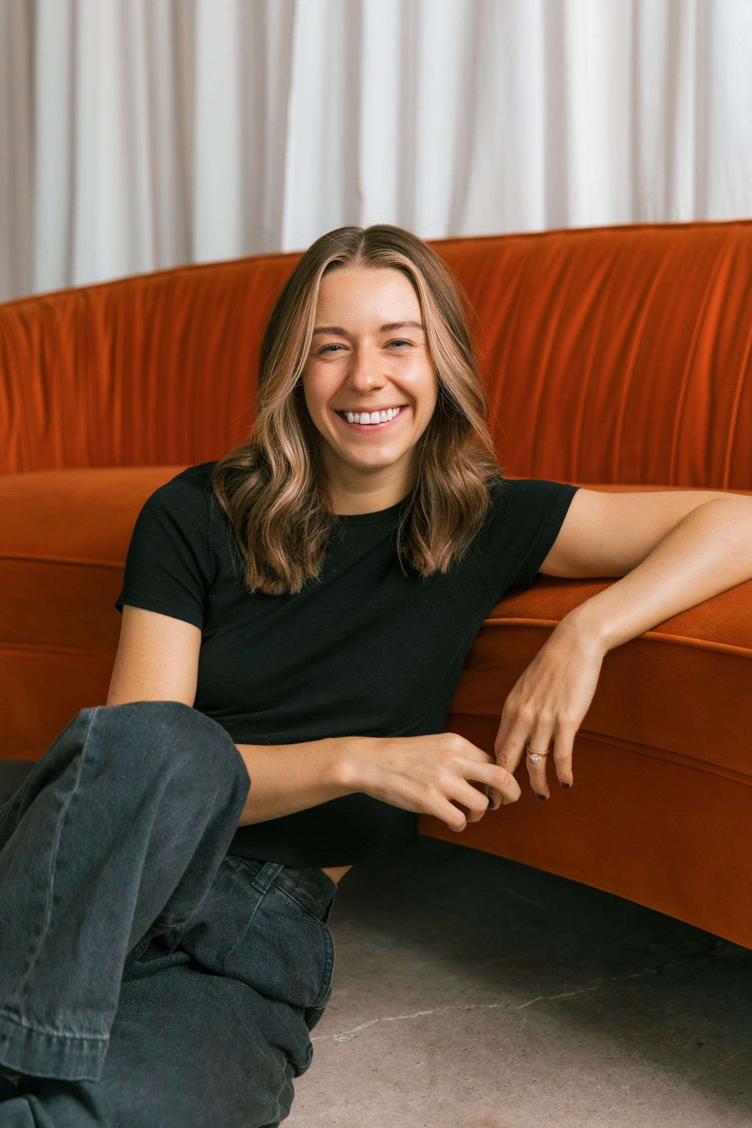 Casual portrait series showing someone relaxing on an orange couch in black clothing.