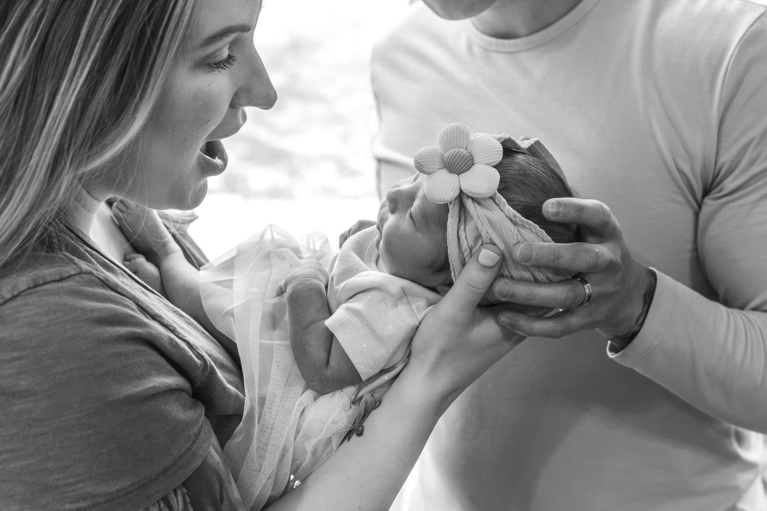 Tender black and white moments between parent and infant in natural window light.