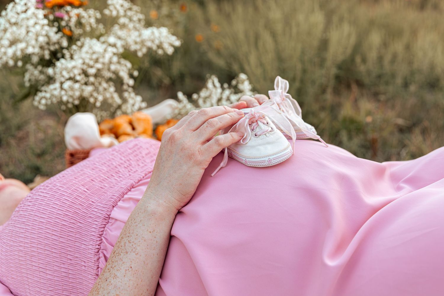 A close-up of delicate baby's breath flowers against a pink maternity dress.