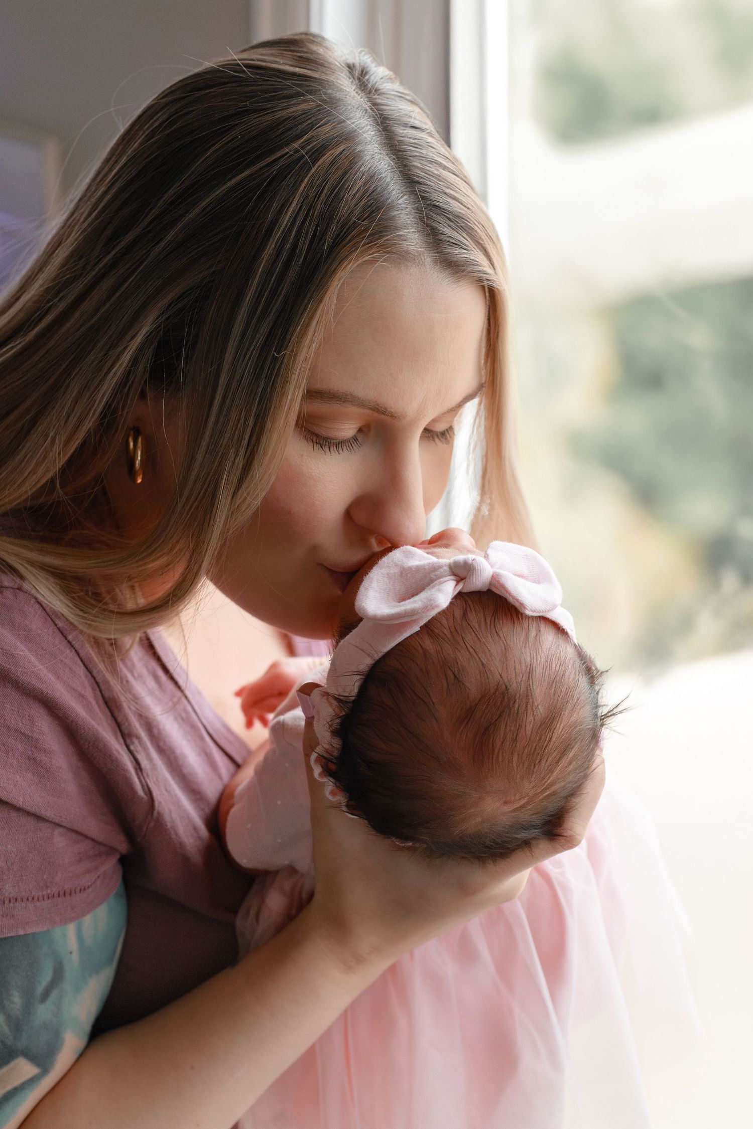 Intimate moments between parent and baby in soft natural window lighting.